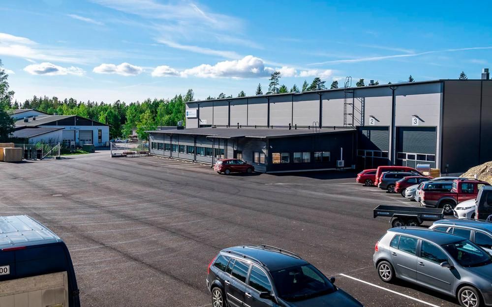 Suuri varasto, jossa on pysäköintialue ja useita pysäköityjä autoja sinisen taivaan alla