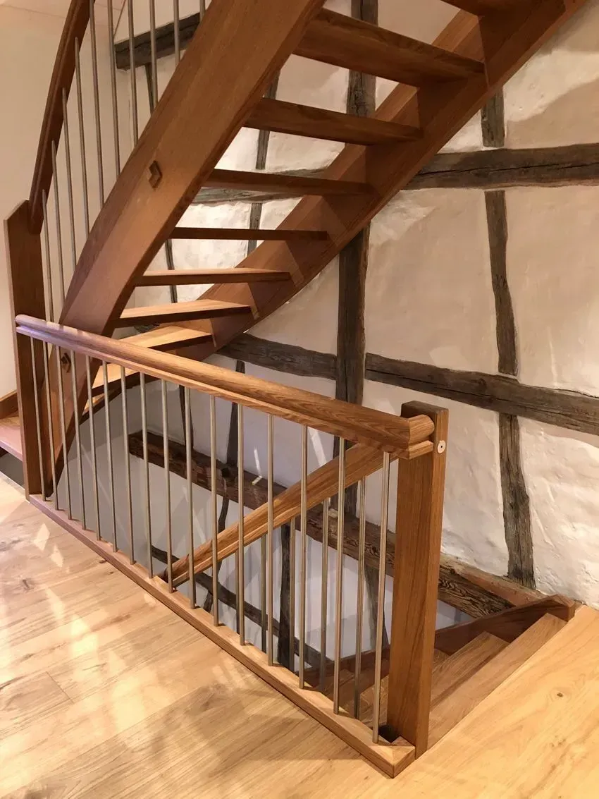 Holztreppe mit Geländer in einem rustikalen Interieur, Blick über eine Balkonöffnung.