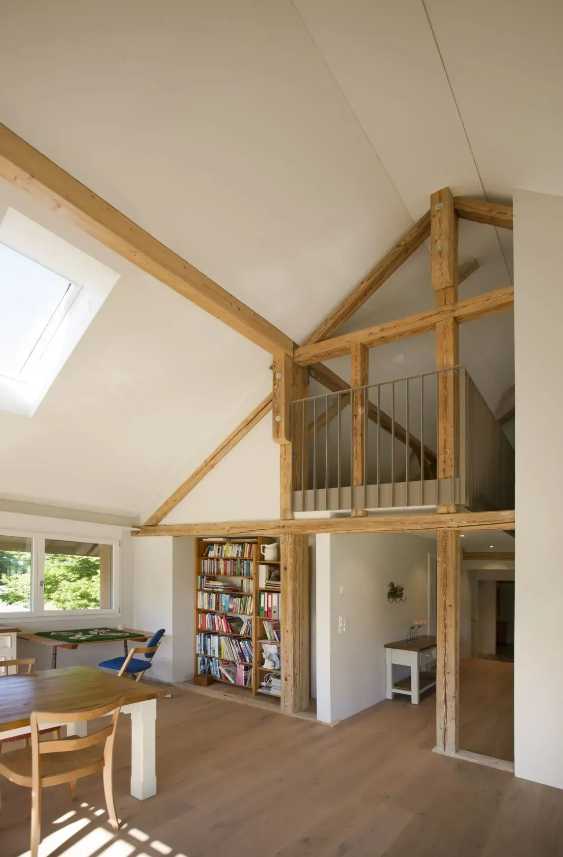 Helles Loft-Wohnzimmer mit hoher Holzdecke, Oberlicht und Treppe zu einem Zwischengeschoss.
