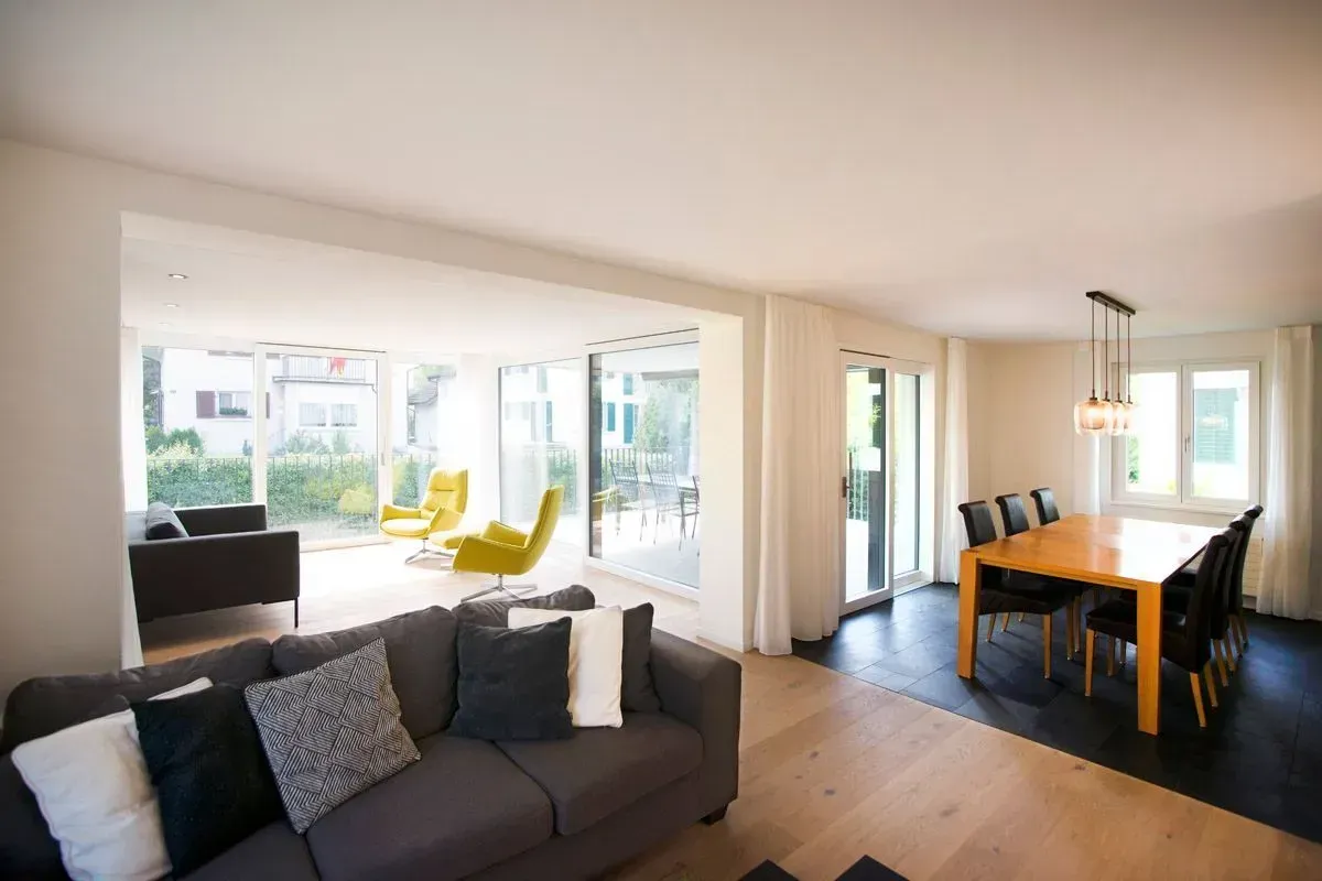 Helles, modernes offenes Wohn- und Esszimmer mit Sofa, gelben Stühlen und großen Glasschiebetüren.