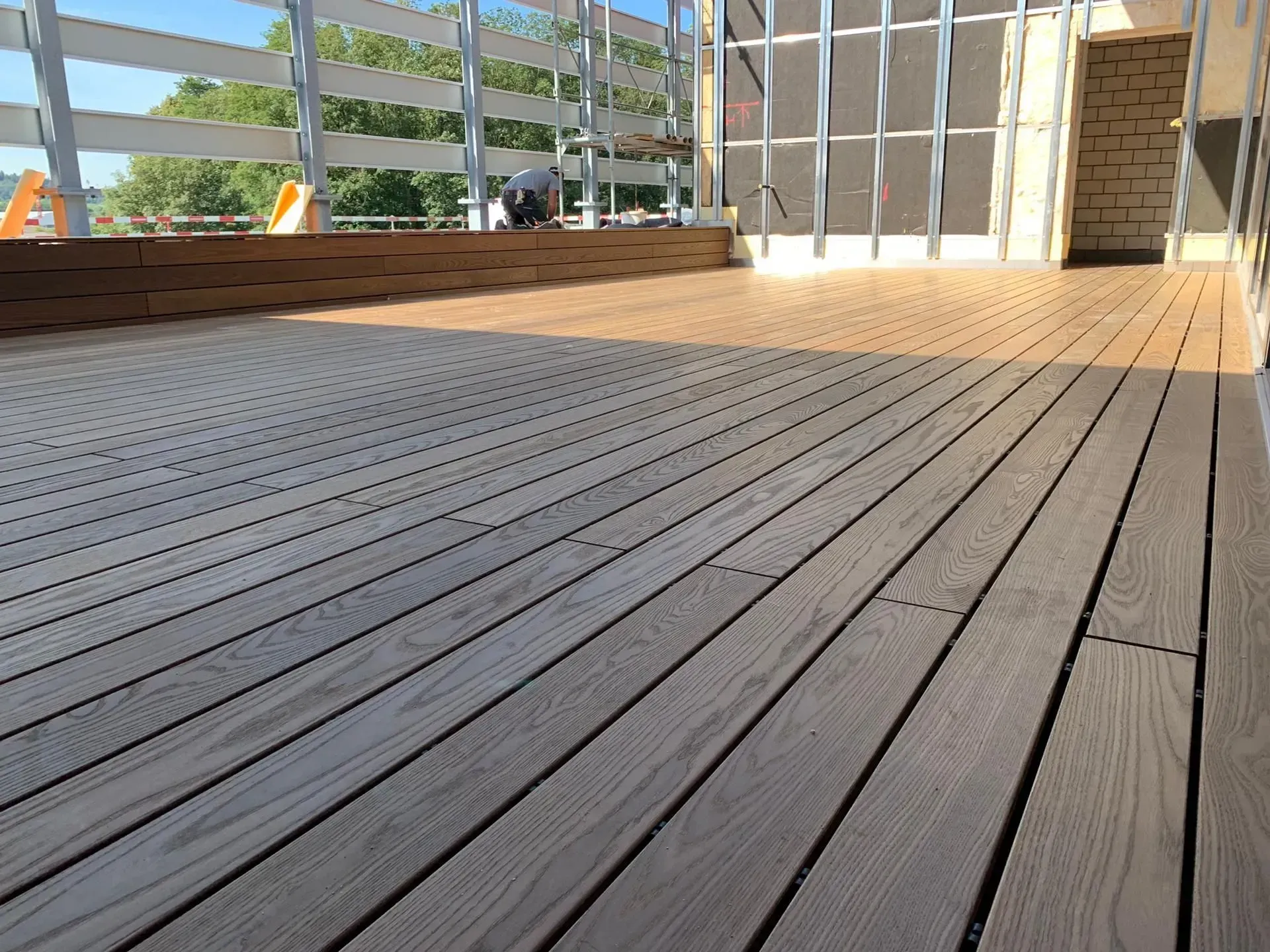 Holzterrasse auf dem Dach mit Lattengeländer und einem hellen, offenen Sitzbereich