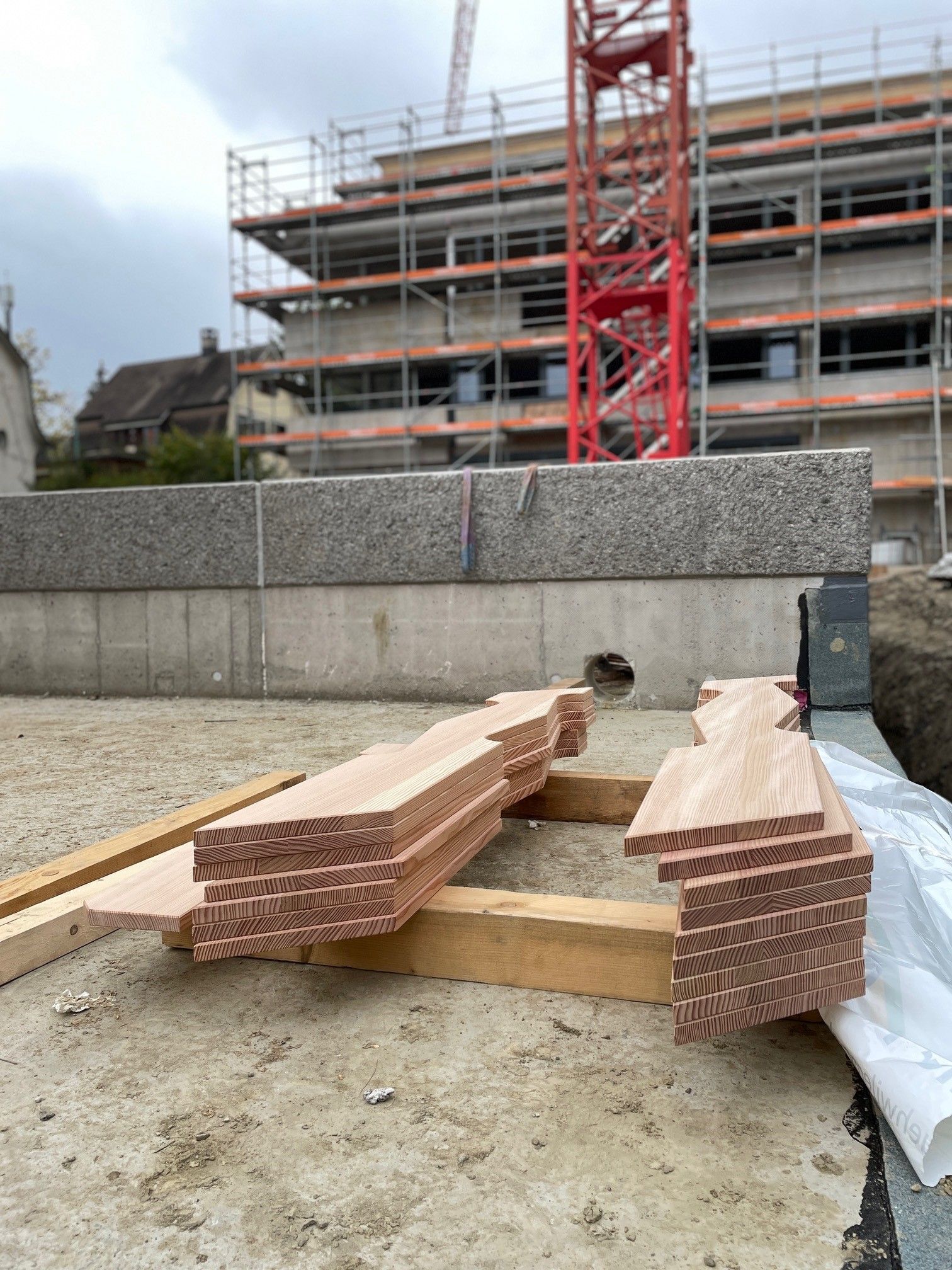 Stapel roter Lehmziegel auf einer Baustelle vor einem Gebäude, das renoviert wird.