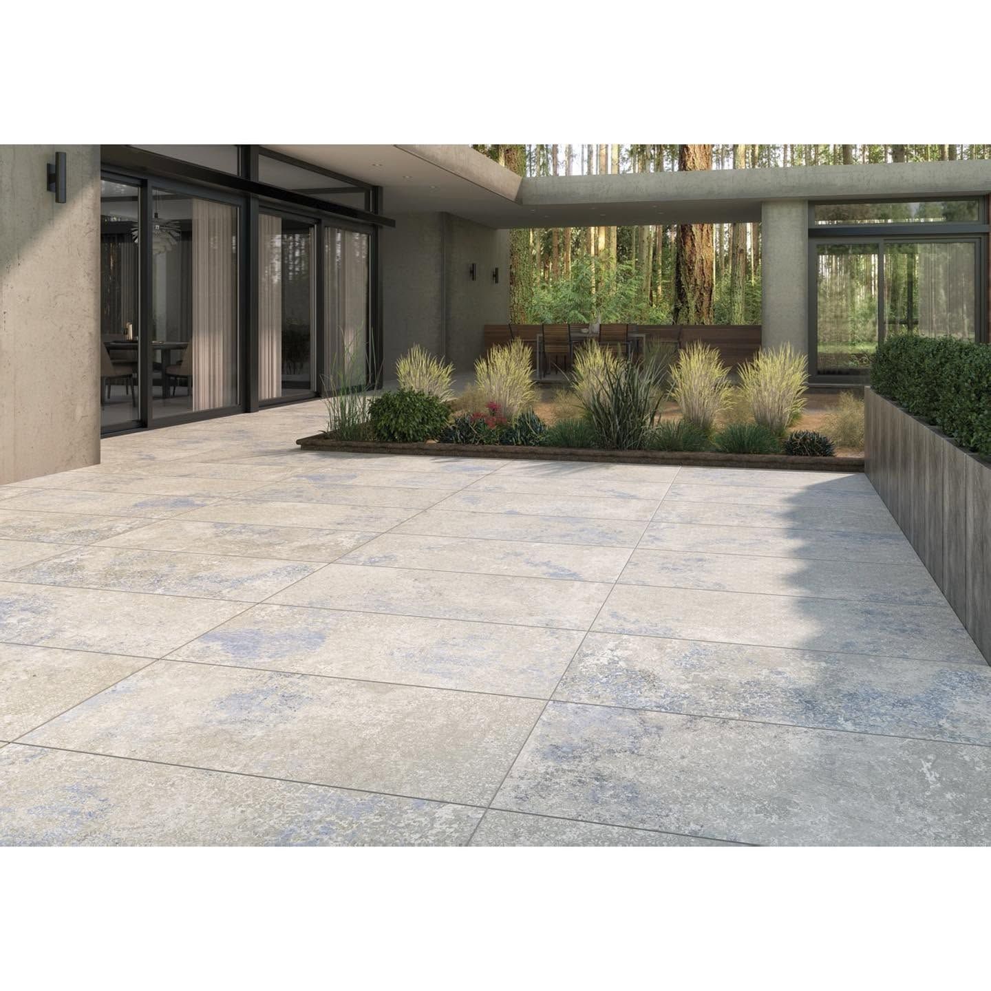 Cour intérieure d'un appartement moderne avec grande terrasse en pierre, jardinières et portes vitrées
