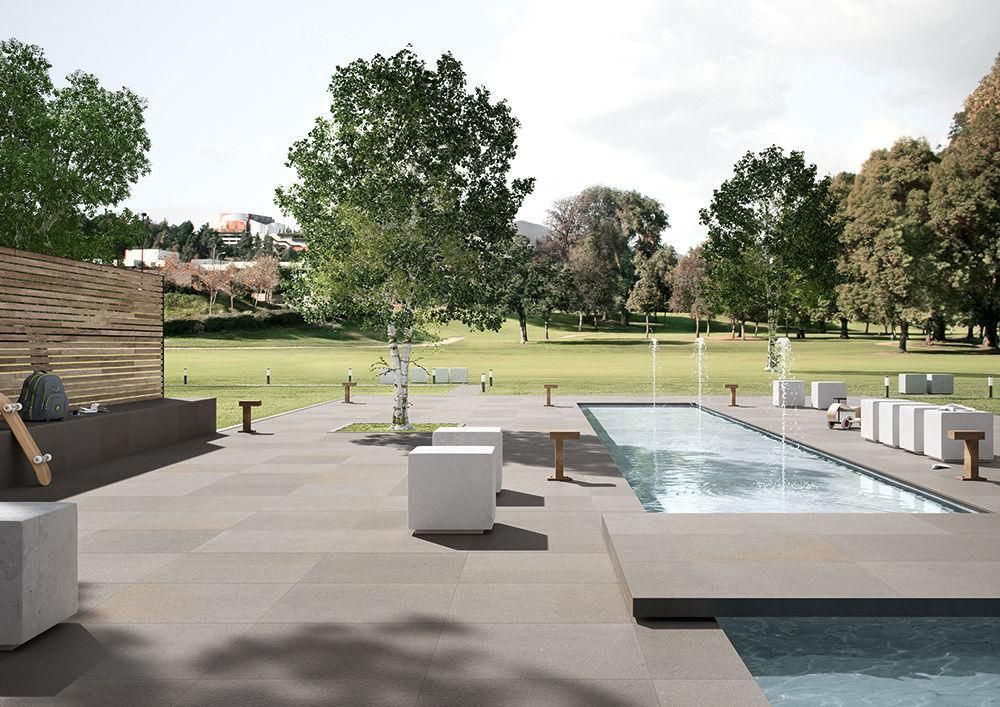 Terrasse moderne dans la cour arrière avec fontaine, salon de jardin et arbres donnant sur un parc avec du gazon.
