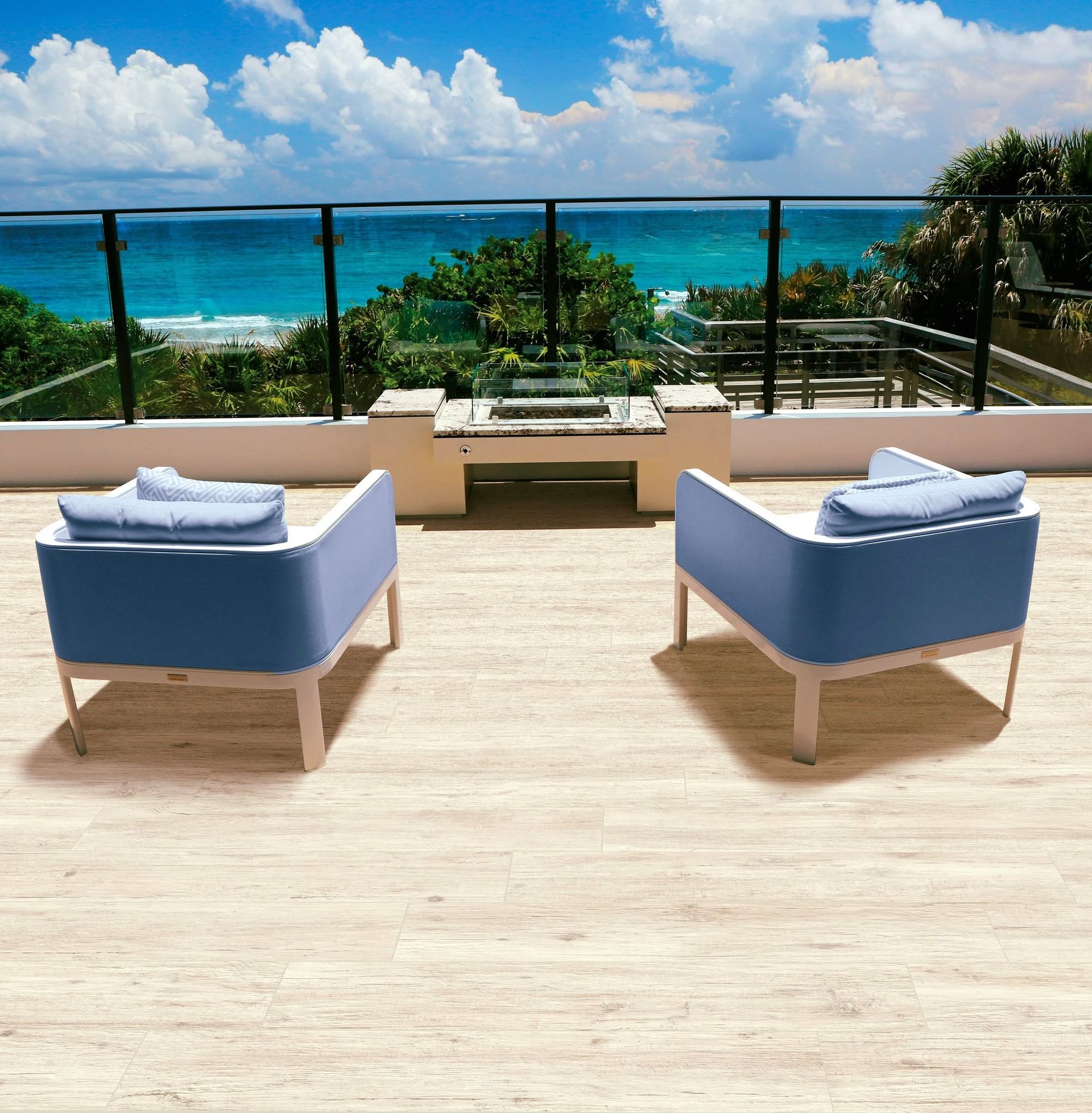 Terrasse avec vue sur l'océan, aménagée avec deux chaises longues bleues face à une eau turquoise et un ciel lumineux.