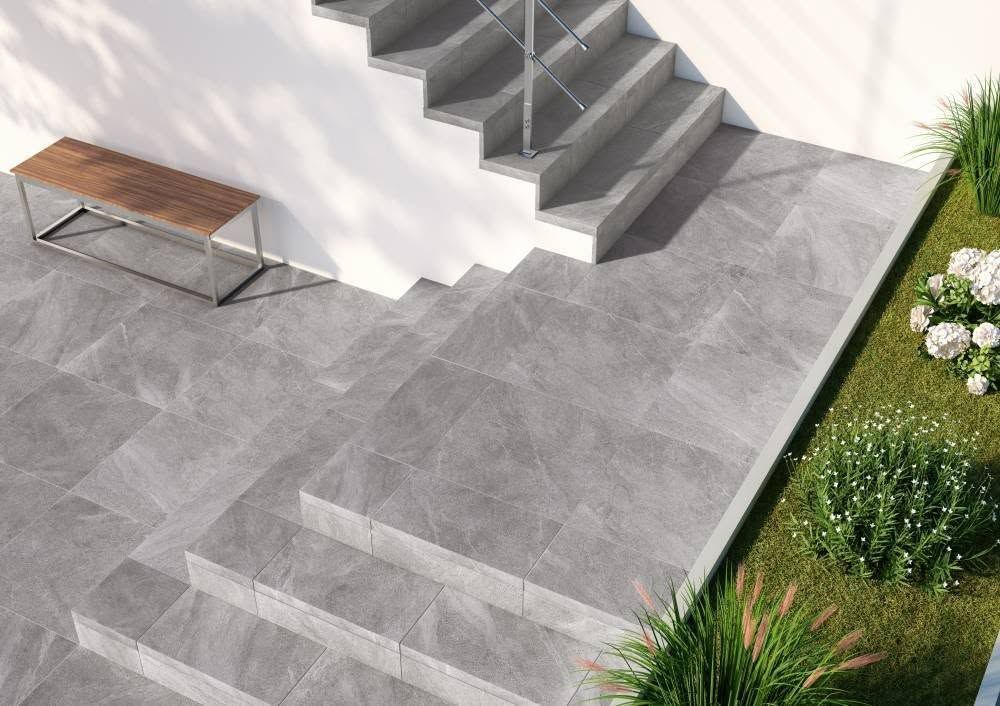 Terrasse extérieure moderne avec marches en pierre grise, banc et aménagement paysager verdoyant.