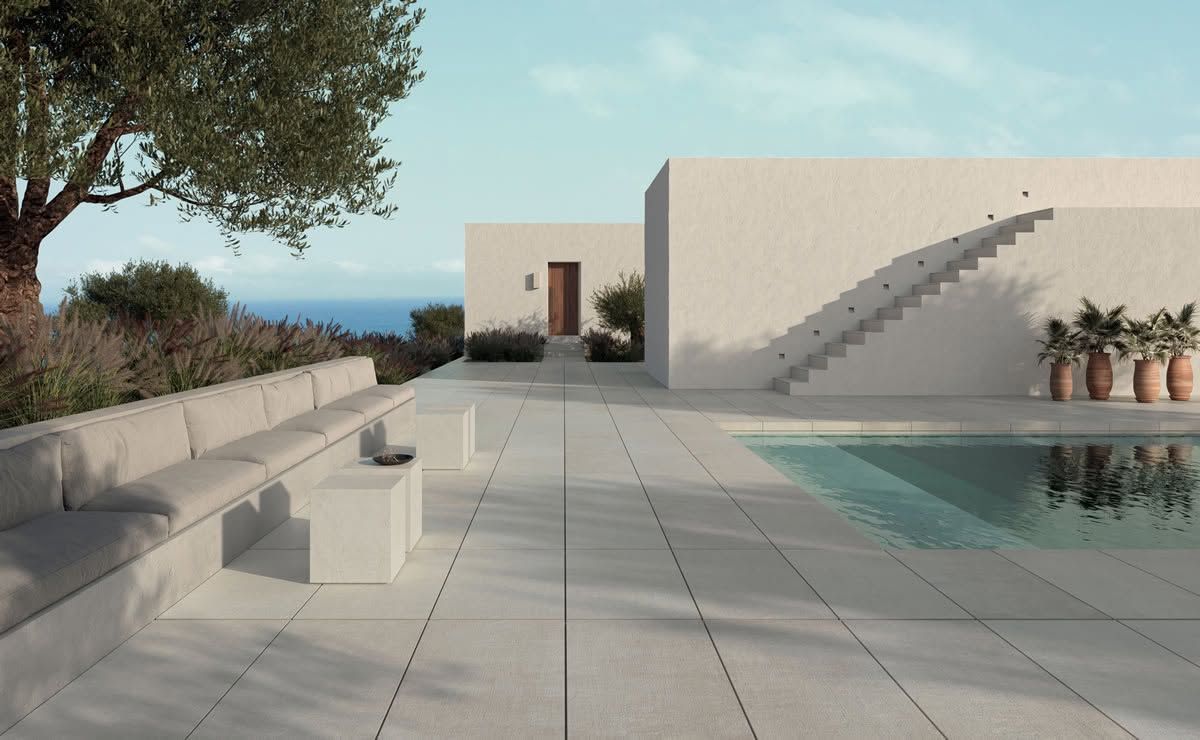 Cour intérieure moderne avec piscine, sièges en béton, escaliers et vue dégagée sur la mer sous un arbre