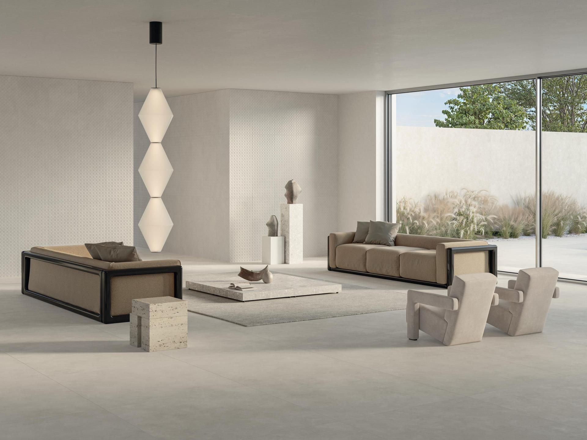 Salon moderne minimaliste beige avec canapés bas, fauteuils et grandes fenêtres donnant sur la verdure.