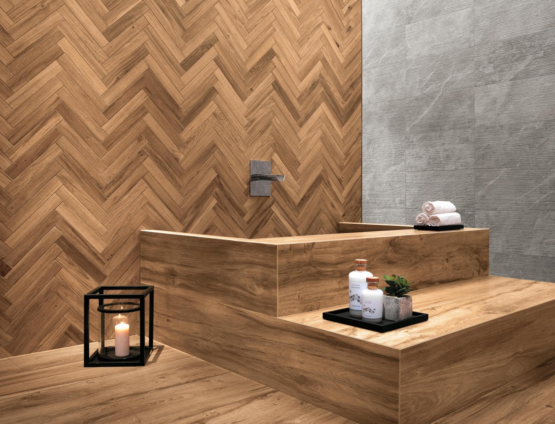 Espace bain en bois façon spa avec bougie lanterne, plante en pot et serviettes pliées sur les marches