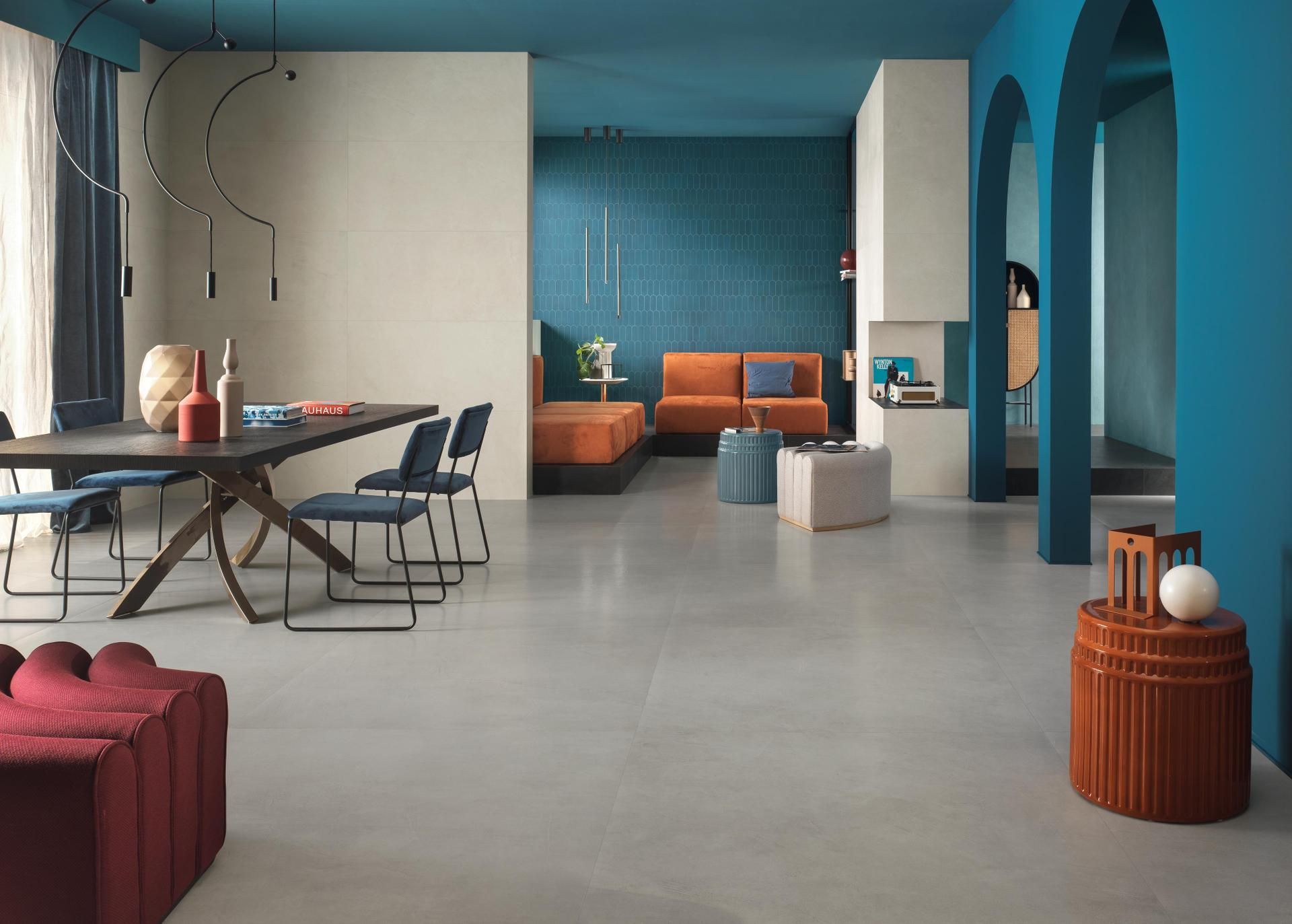 Salon moderne à aire ouverte avec murs turquoise, canapé orange, table à manger et arches bleues.