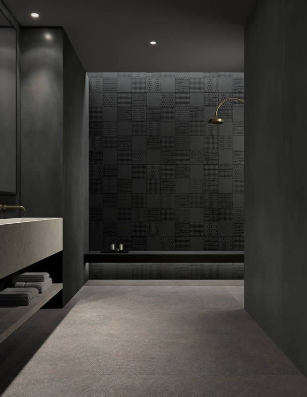 Salle de bains moderne et sombre avec sol gris, paroi de douche carrelée noire et lavabo minimaliste.