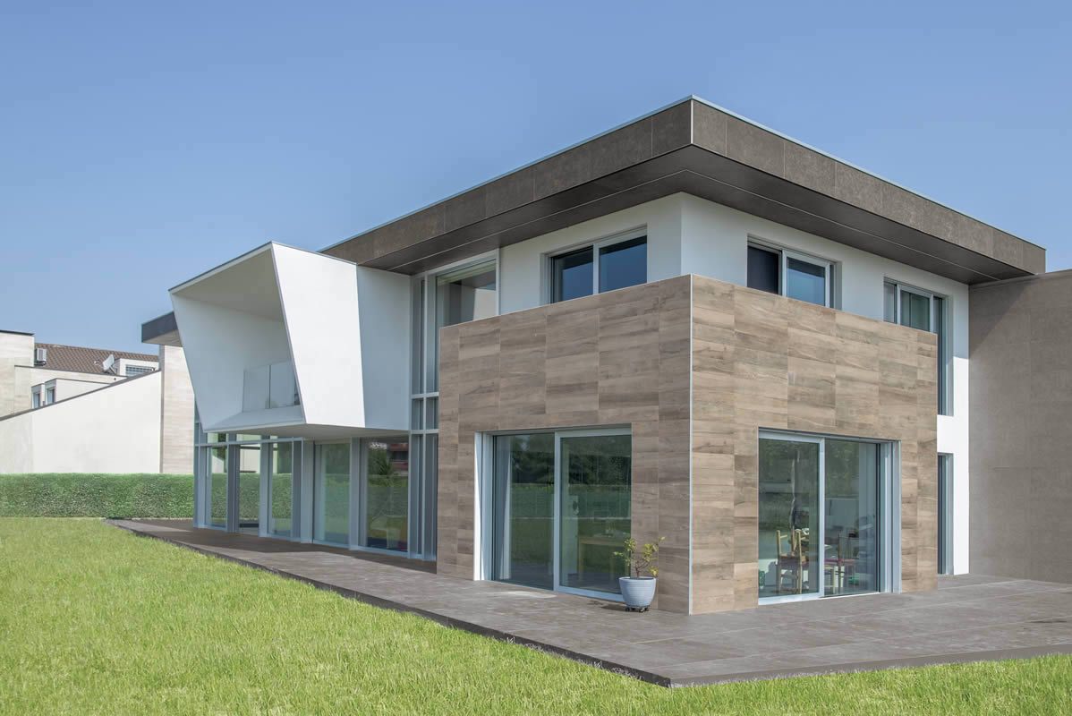 Maison moderne à deux étages avec de grandes fenêtres, un extérieur blanc et en bois et une pelouse verte