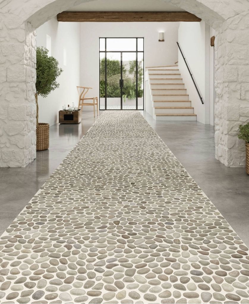 Mur en pierre avec quelques herbes et plantes éparses à sa base, à côté d'une allée moderne.