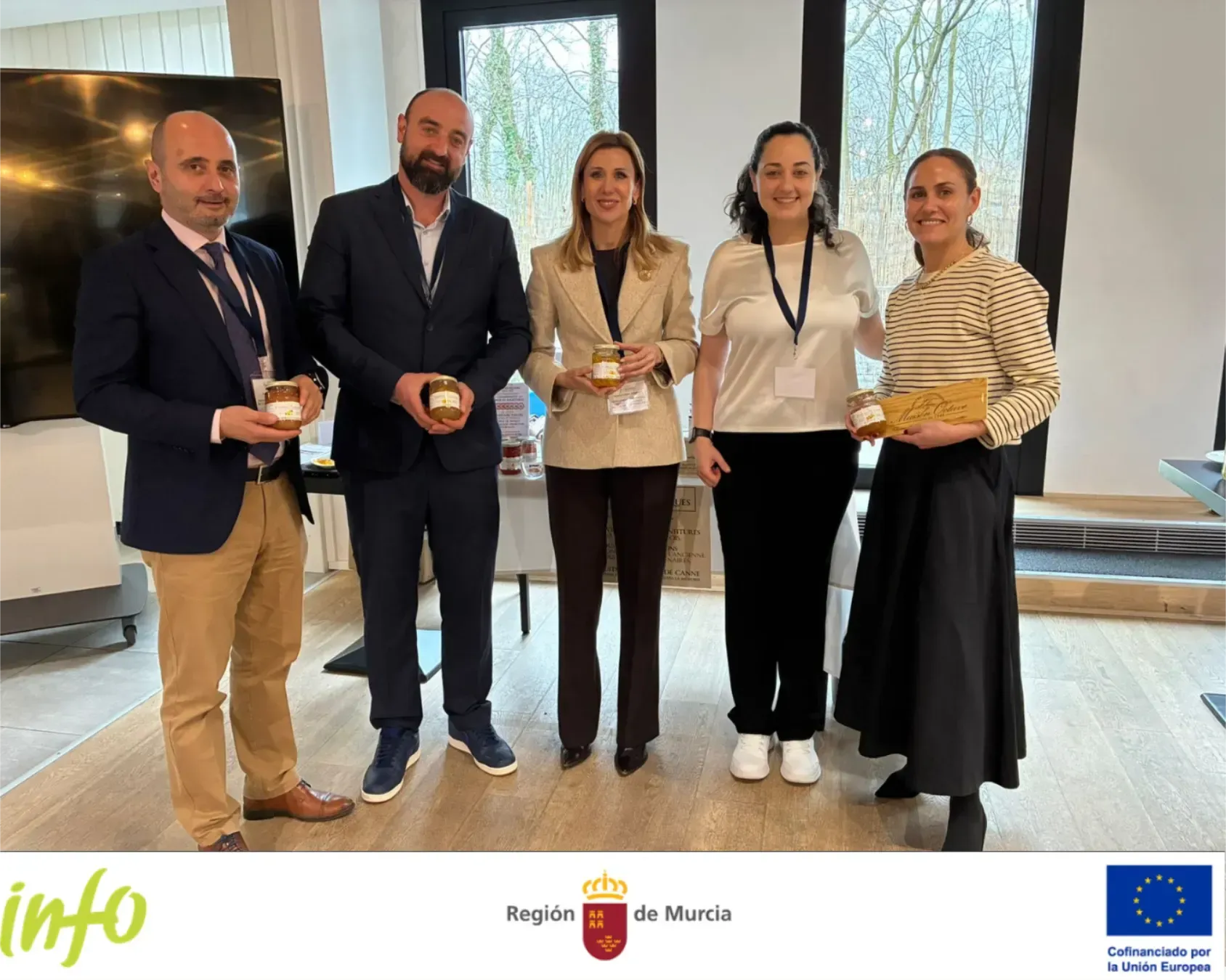 Cinco personas que sostienen premios permanecen de pie en el interior de una ceremonia