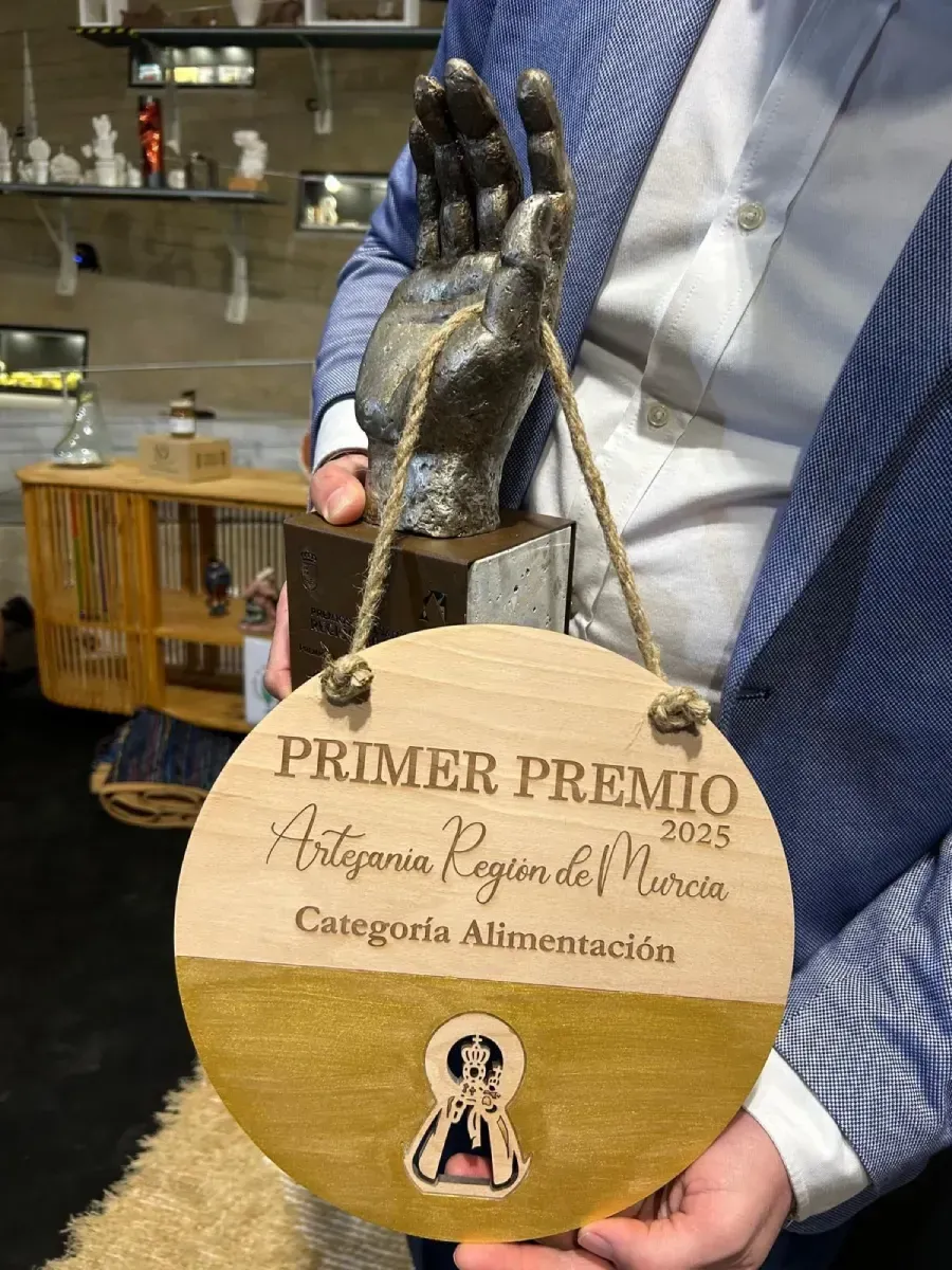 Persona sosteniendo una placa de trofeo dorada con las inscripciones “PRIMER PREMIO” y “Antigua y Limpia”