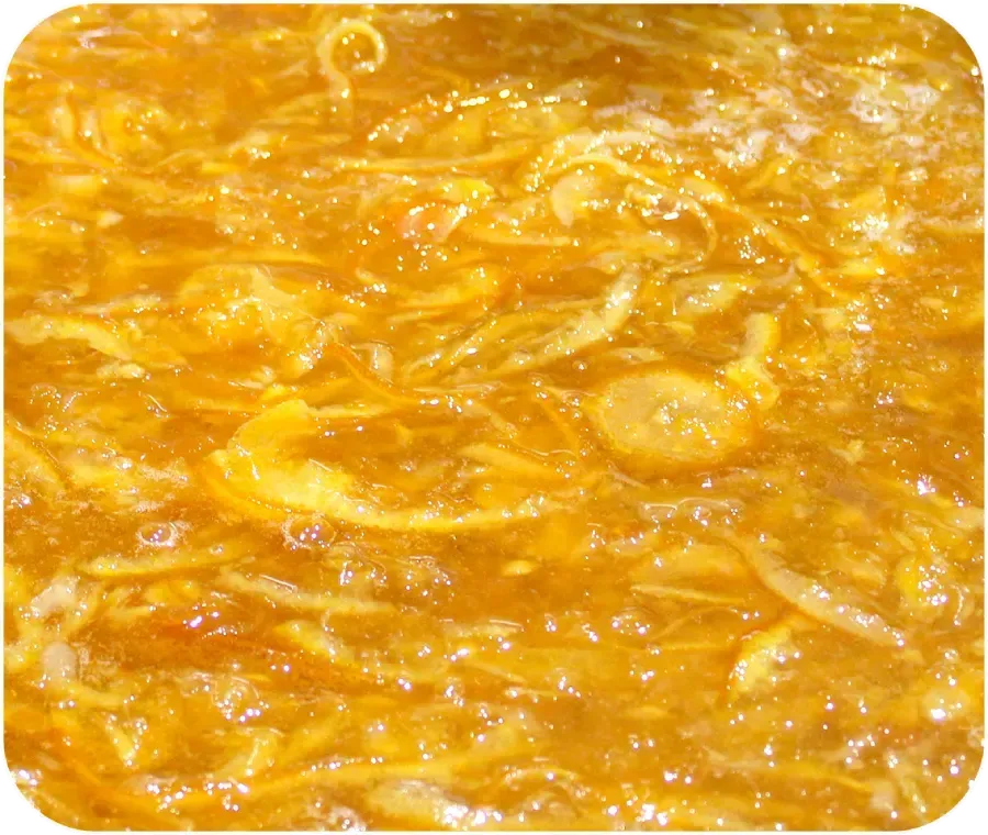 Primer plano de fruta rallada o mermelada de color naranja brillante con una superficie texturizada y almibarada.