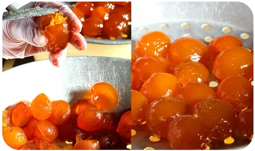 Primer plano de huevas de pescado de color naranja brillante siendo recogidas y vertidas en un recipiente de metal.