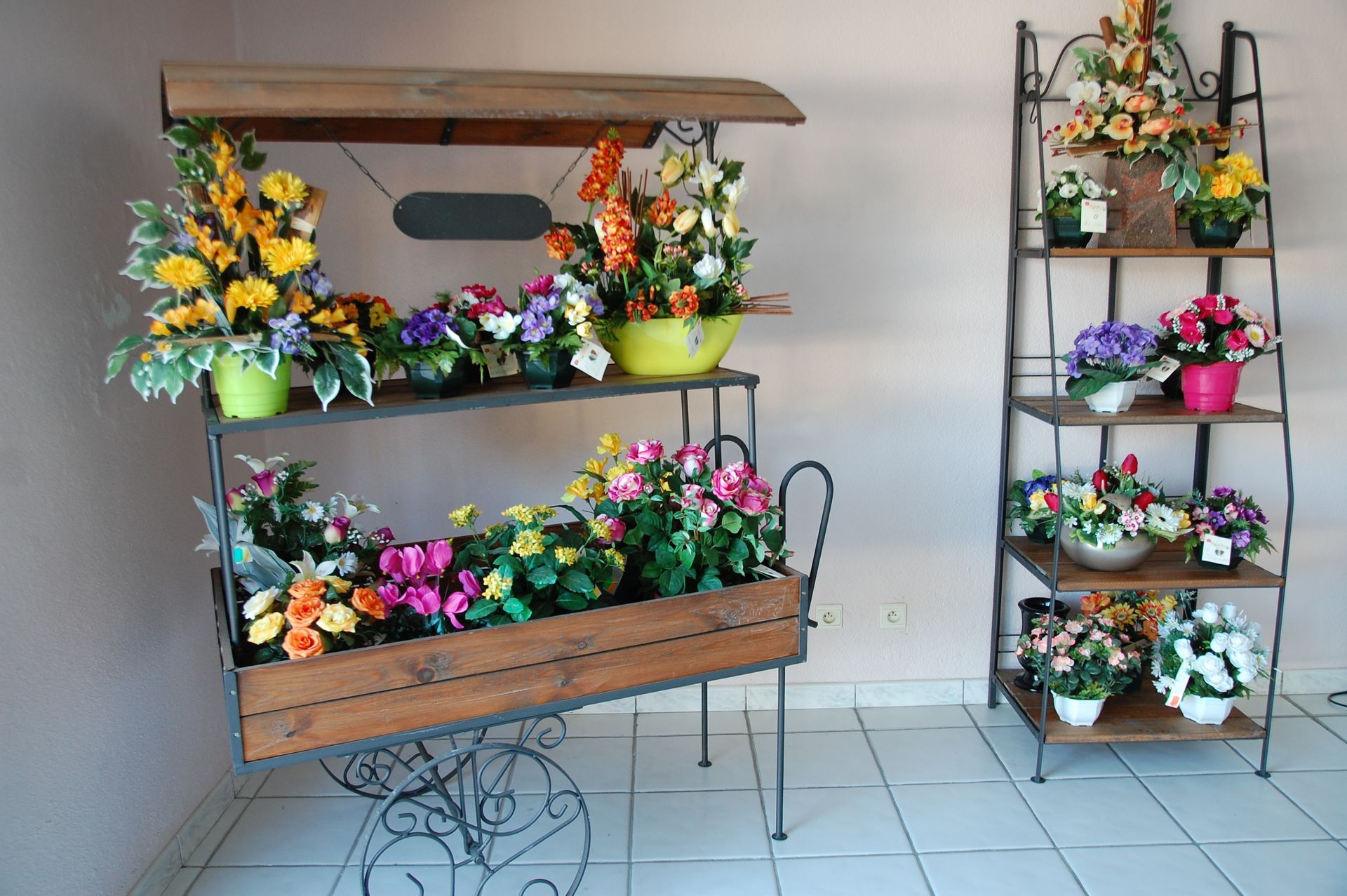 Chariot à fleurs et étagère présentant des compositions florales colorées à l'intérieur.