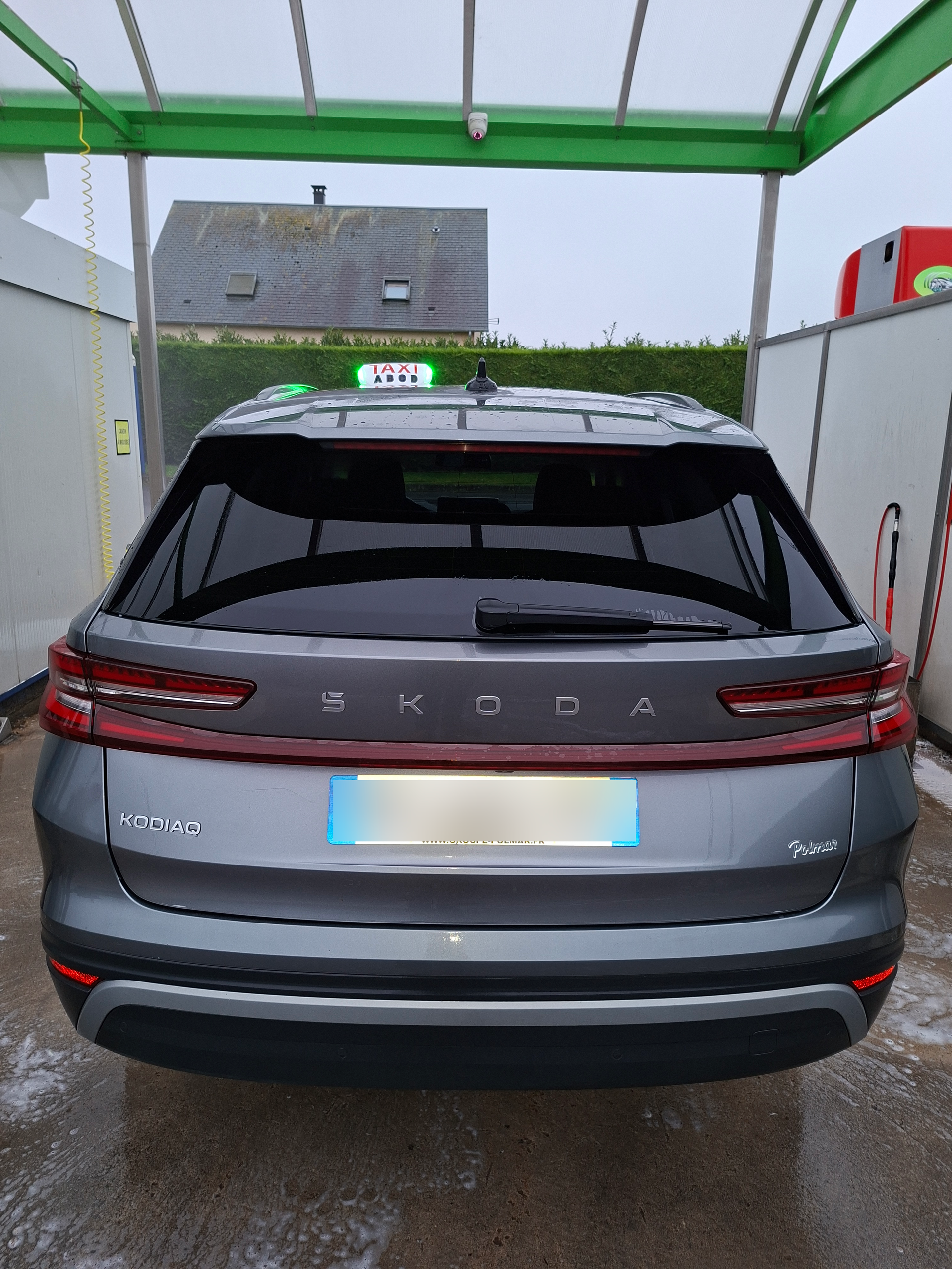 Un SUV Skoda gris dans une station de lavage, avec le nom de la marque inscrit sur le coffre.