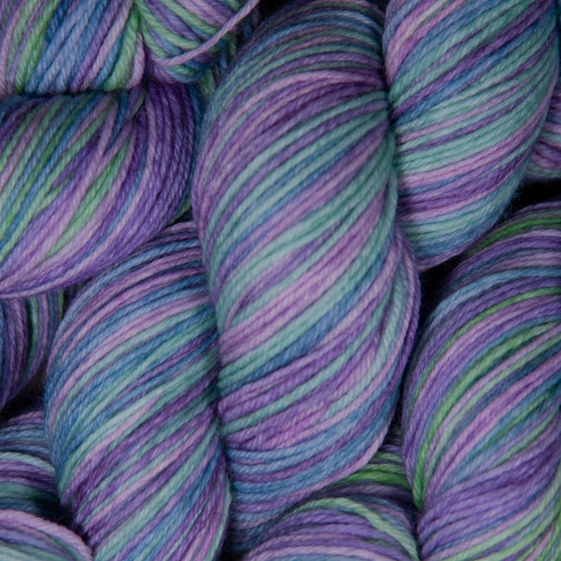 Knäuel buntes Garn, überwiegend blau, lila und grün.