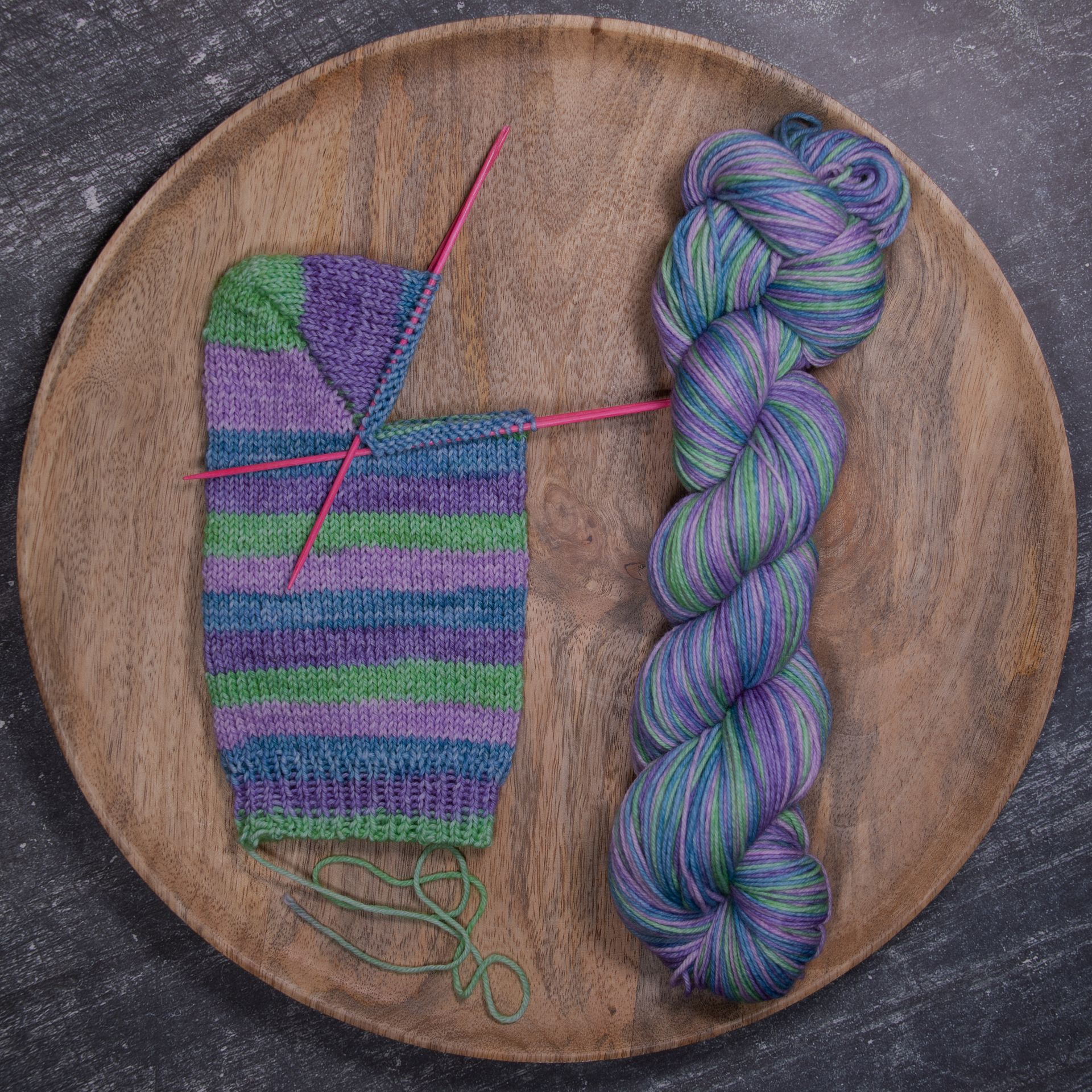 Strickprojekt: Socke in Arbeit, bunte Wolle, Holzteller.