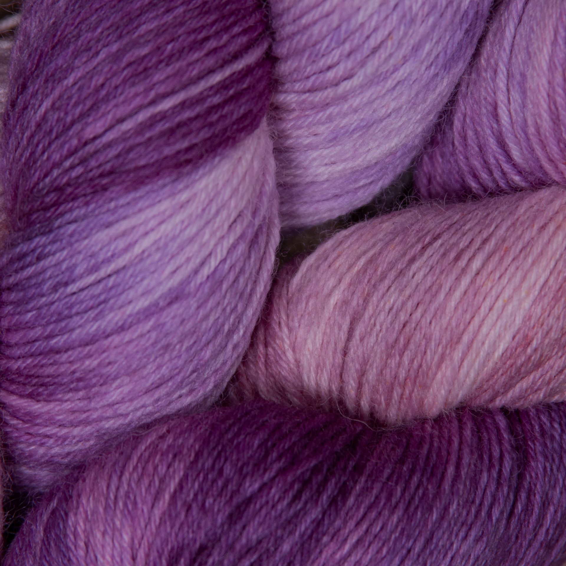 Stränge handgefärbten Garns in verschiedenen Lilatönen, von hellem Lavendel bis zu tiefem Violett.