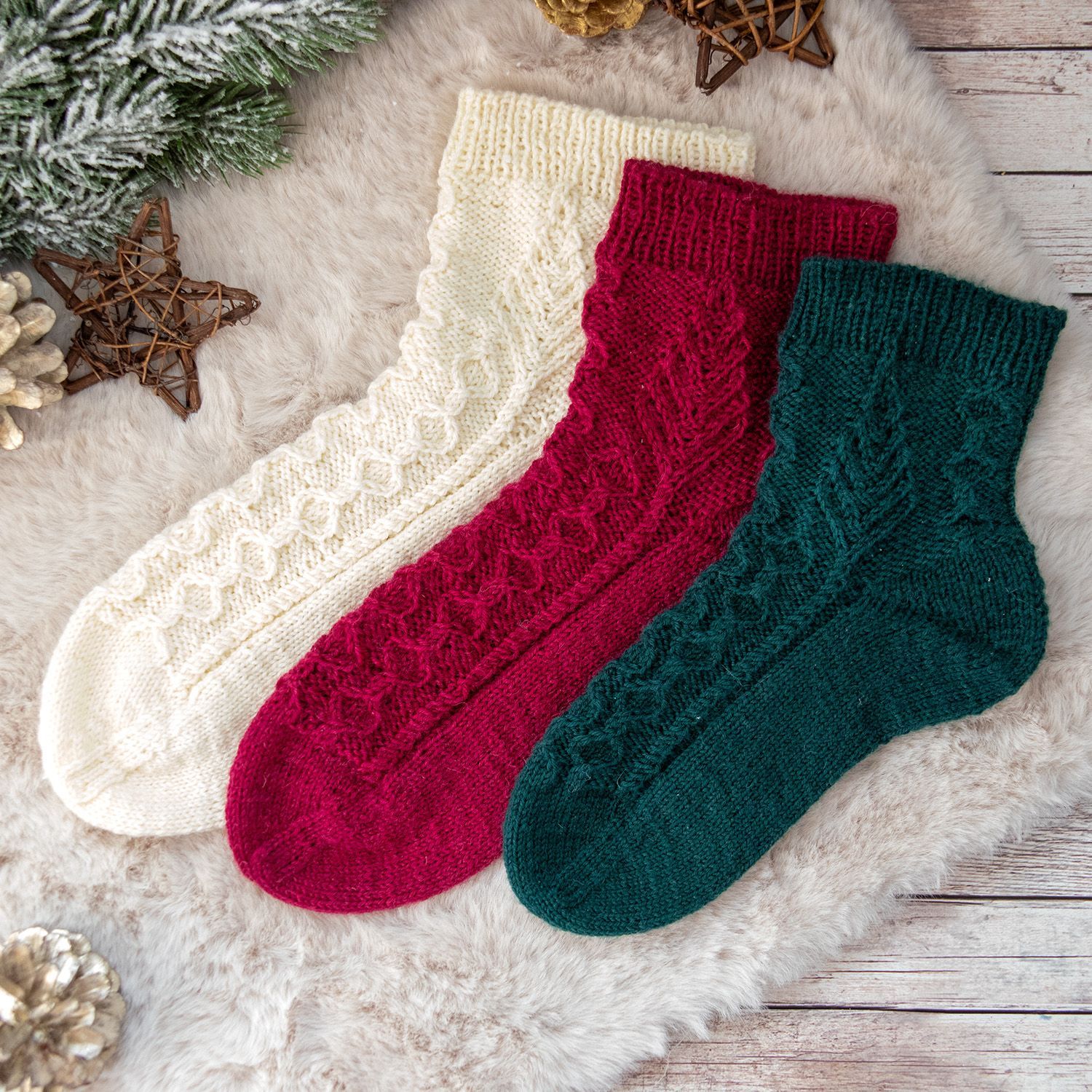 Three Twenty Six – Handgestrickte Weihnachtssocken mit winterlichem Struktur- und Zopfmuster in Creme, Bordeaux und Tannengrün.