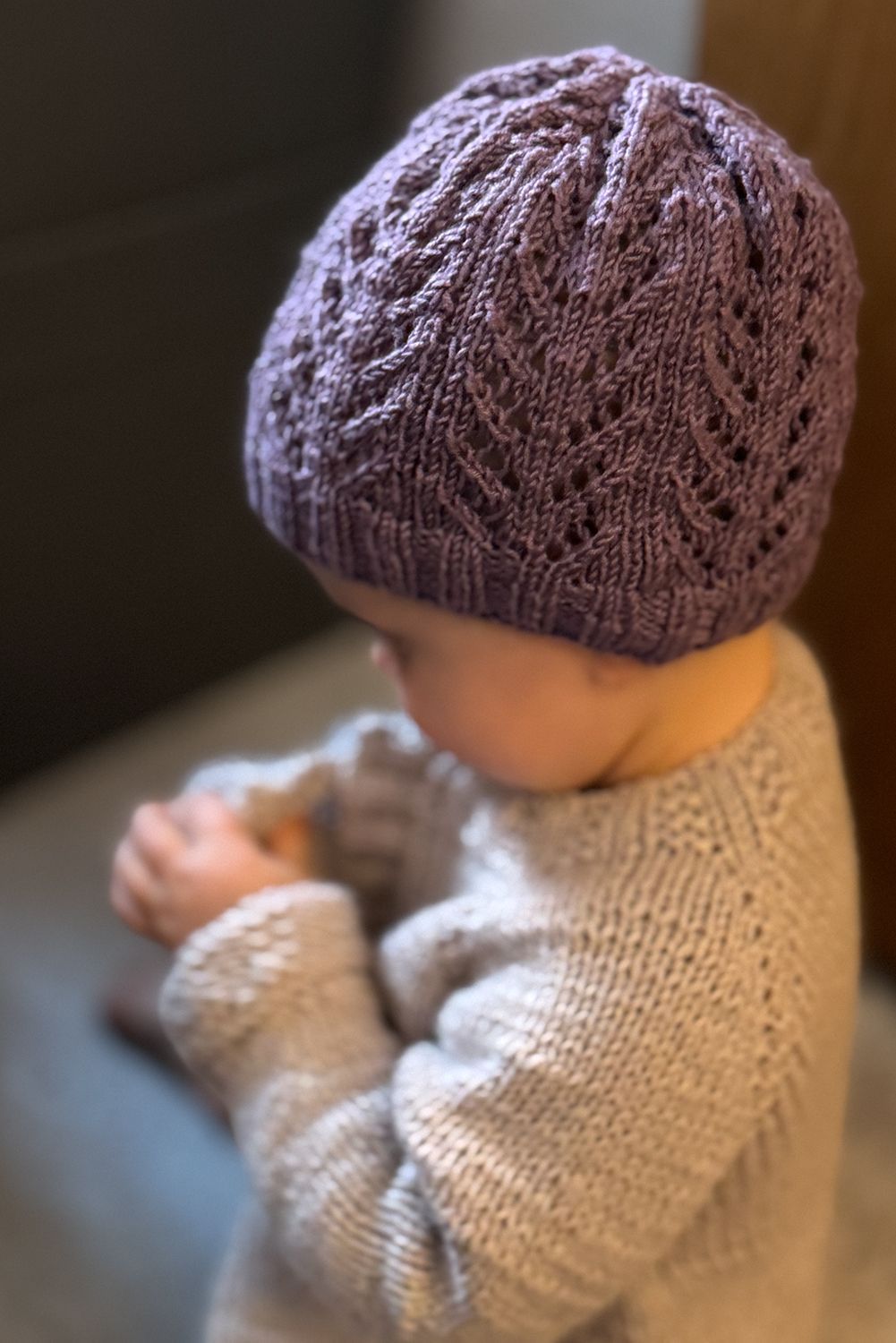 Zwei Strickmützen, eine lila, eine braun, auf holzfarbenem Hintergrund.