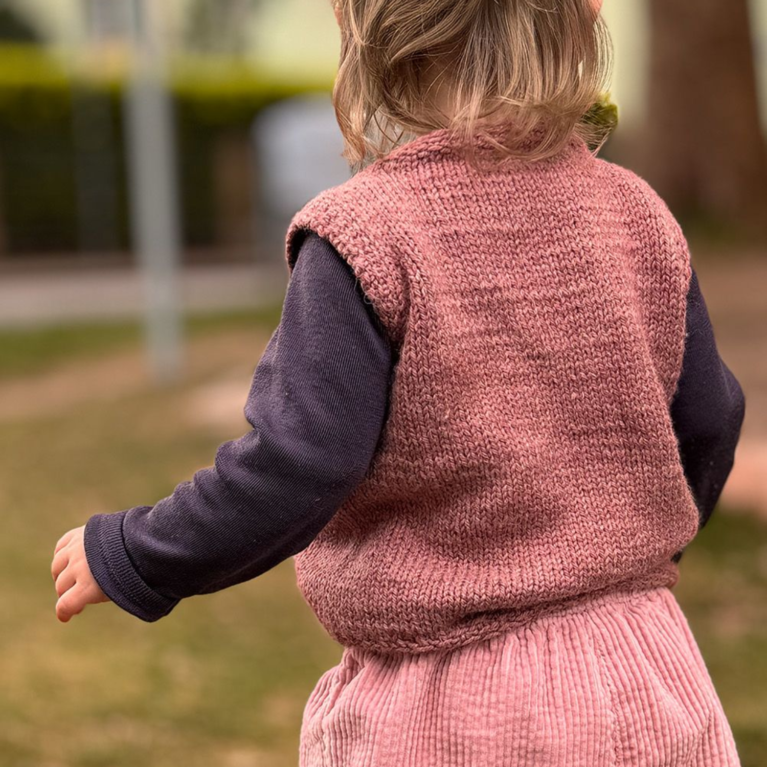 Nahaufnahme einer teilweise fertiggestellten blau-türkis gestrickten Socke, die die Ferse und die Strukturmuster zeigt.