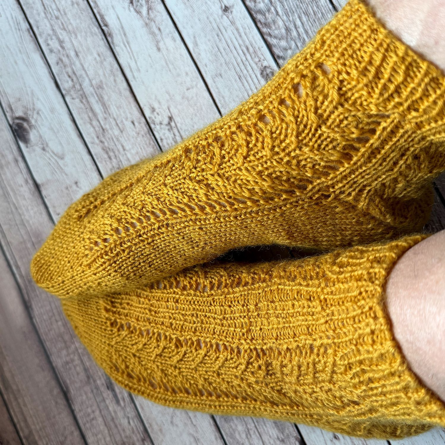 Ein Paar blaue Spitzenstricksocken auf einer Grasfläche.