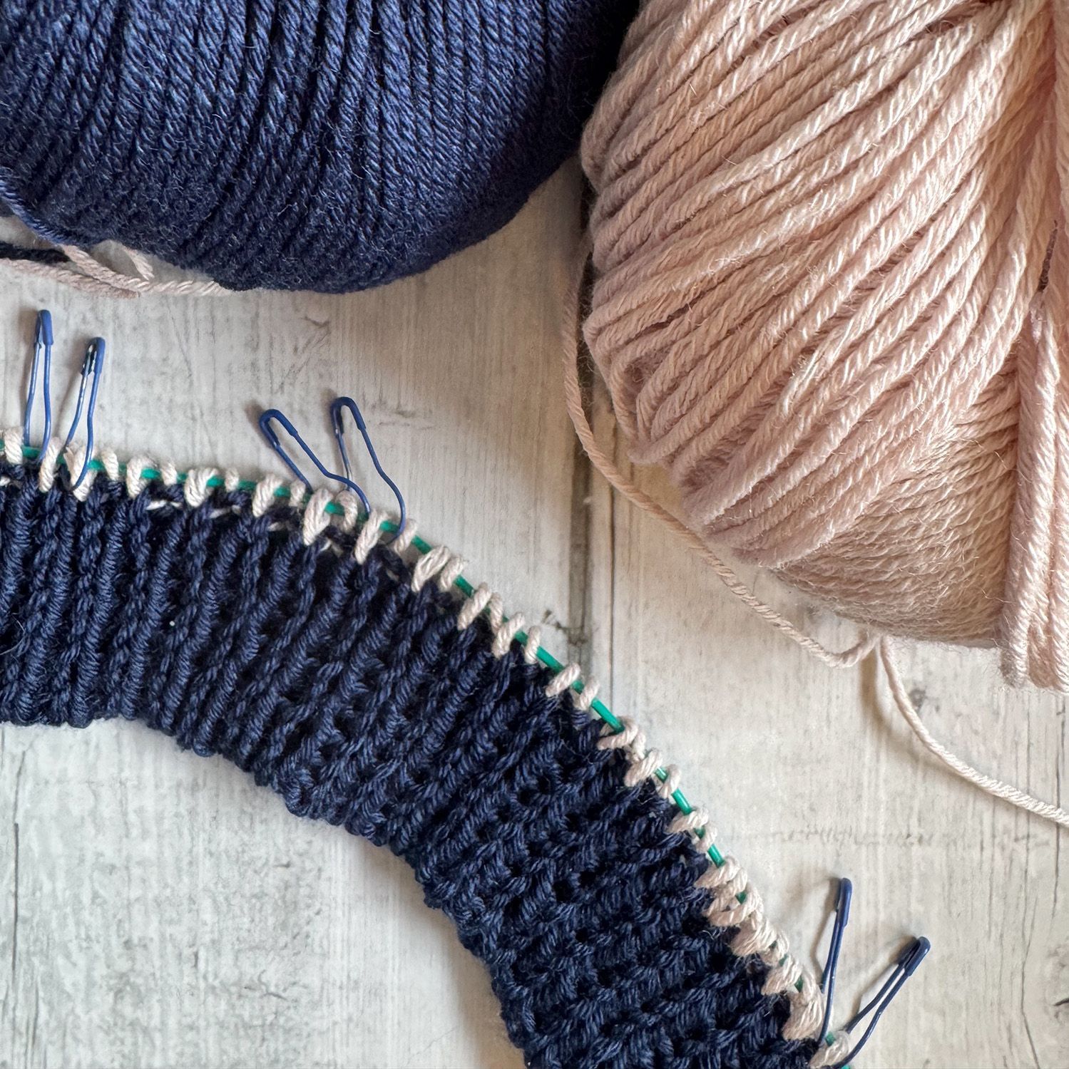 Nahaufnahme einer teilweise fertiggestellten blau-türkis gestrickten Socke, die die Ferse und die Strukturmuster zeigt.