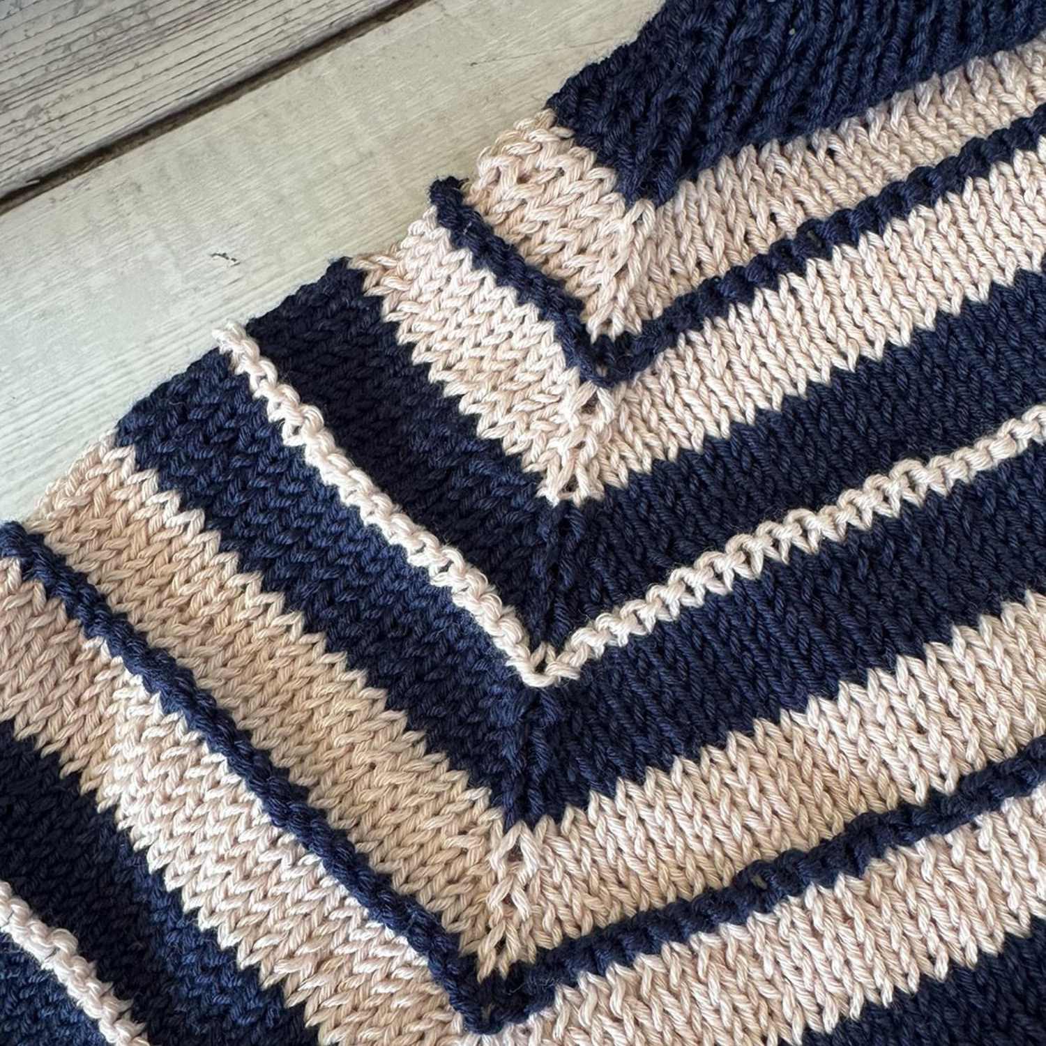 Strickprojekt mit türkisfarbenem und blauem Garn. Rippenmuster, bei dem Nadeln und Wollknäuel sichtbar sind.