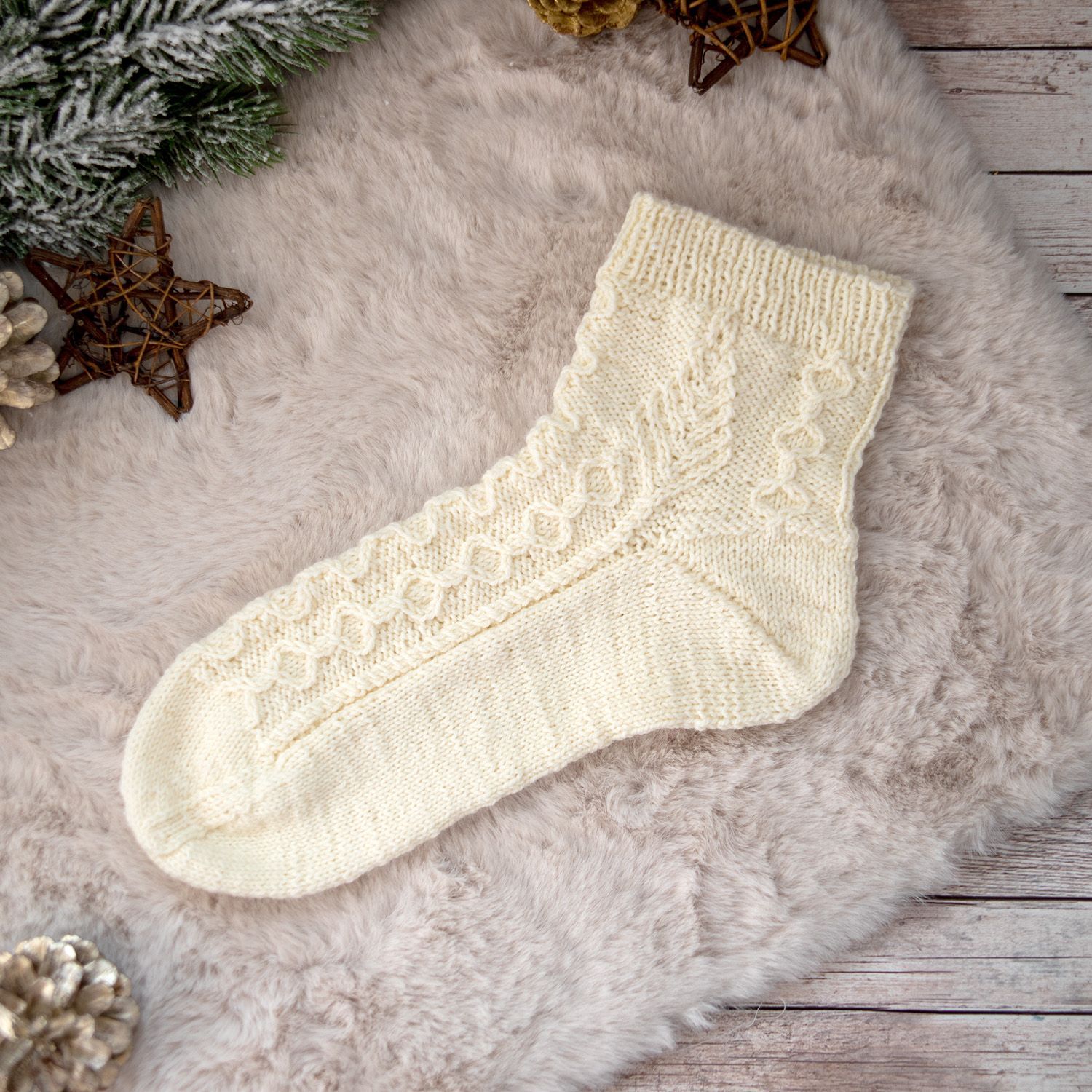 Handgestrickte Socke aus der Strickanleitung Three Twenty Six mit winterlichem Strukturmuster und plastischen Zopfelementen.