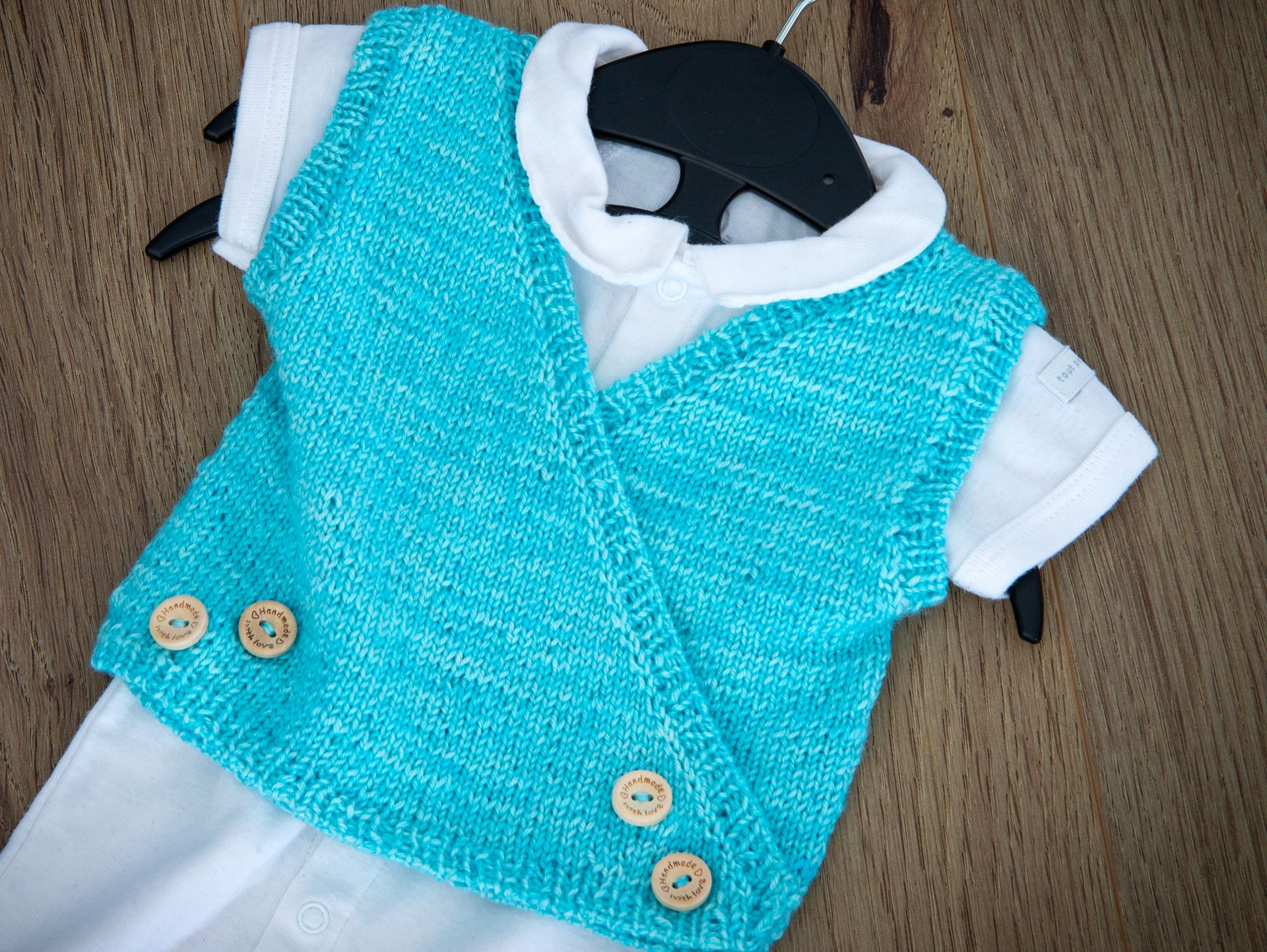 Nahaufnahme einer teilweise fertiggestellten blau-türkis gestrickten Socke, die die Ferse und die Strukturmuster zeigt.