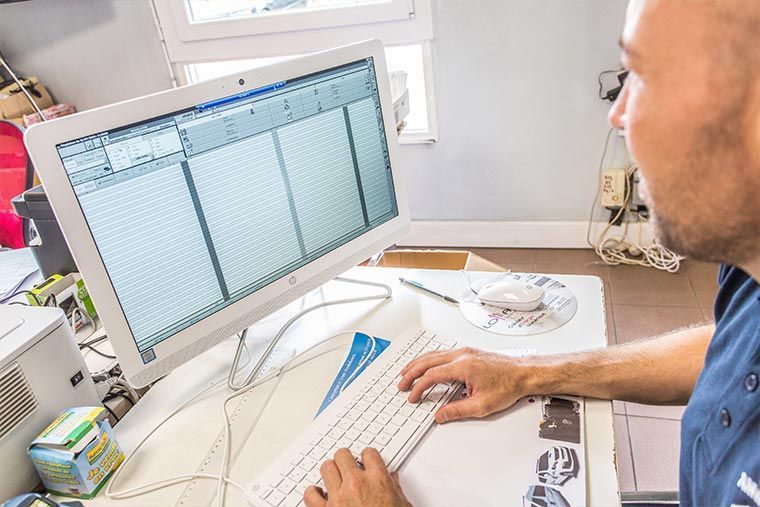 Un homme travaille sur un ordinateur avec un clavier et un écran blancs.