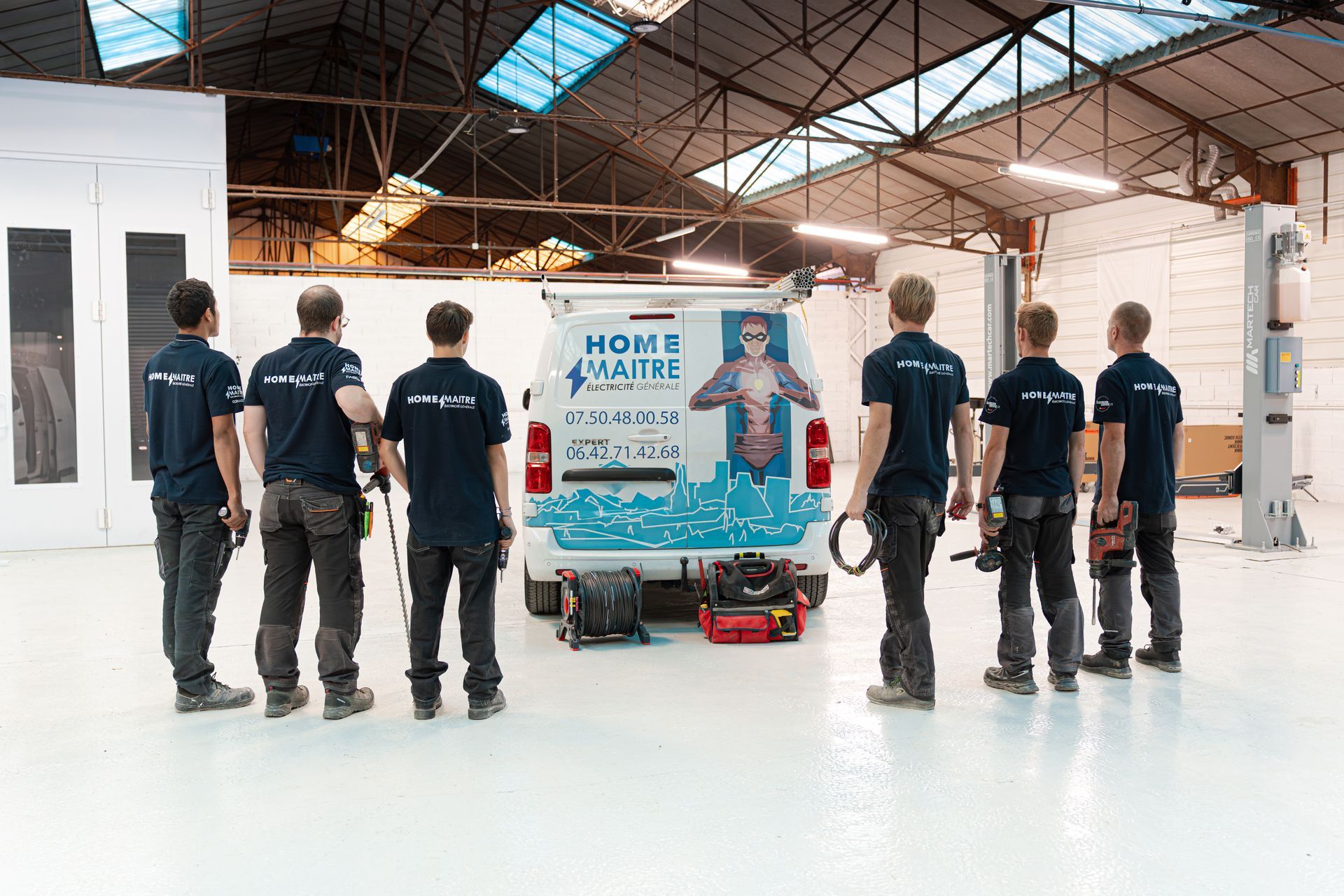 Equipe de 6 personnes devant un camion d'entreprise avec un super-héros floqué dessus représentan la marque de l'entreprise Homemaitre