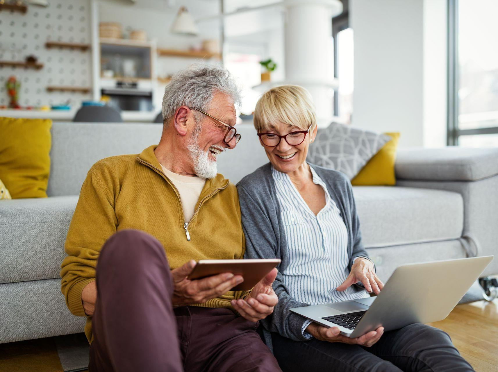 Un homme et une femme devant un ordinateur portable et une tablette