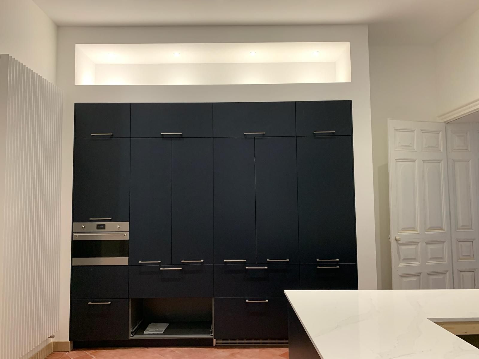 Une cuisine avec des armoires bleu foncé et des comptoirs blancs