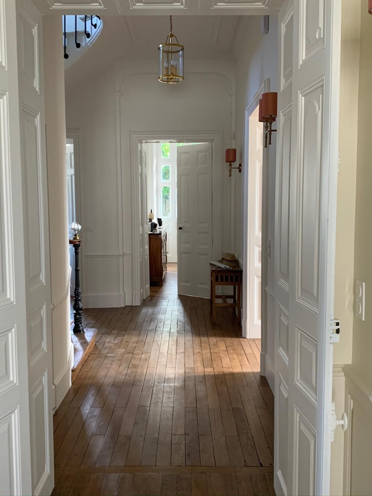 Un couloir avec du parquet et des portes blanches dans une maison.