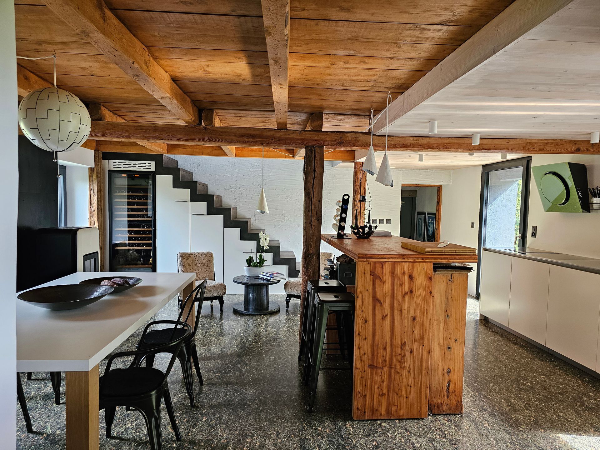 Une cuisine avec une table et des chaises en bois et un escalier en bois.
