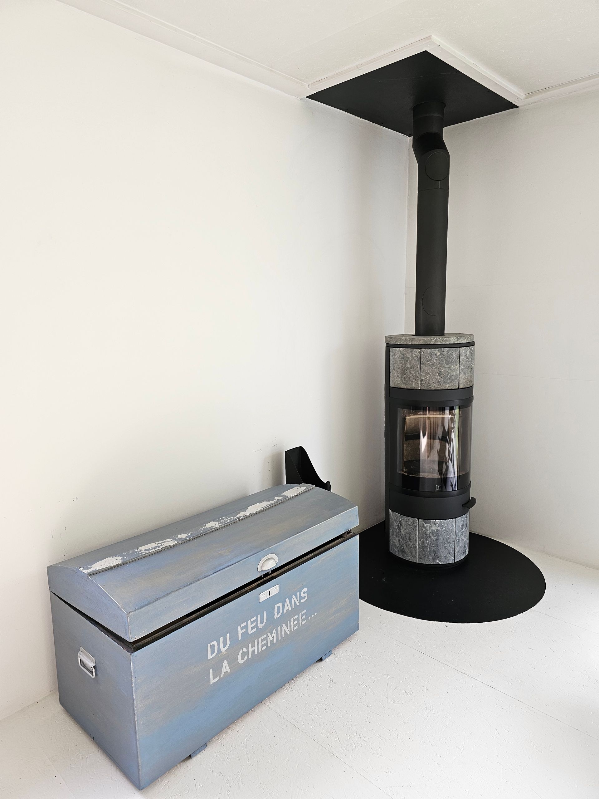 Un poêle à bois est posé dans un coin à côté d'un coffre