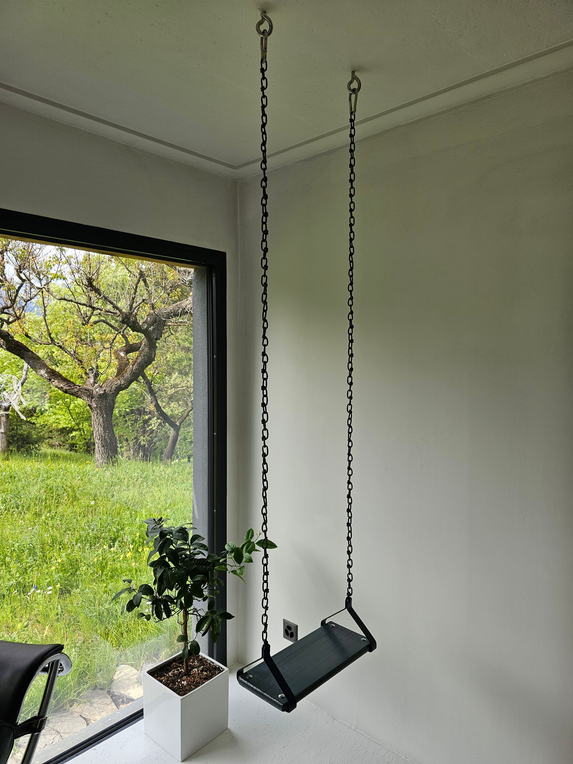 Deux balançoires sont suspendues au plafond dans une pièce à côté d'une fenêtre.