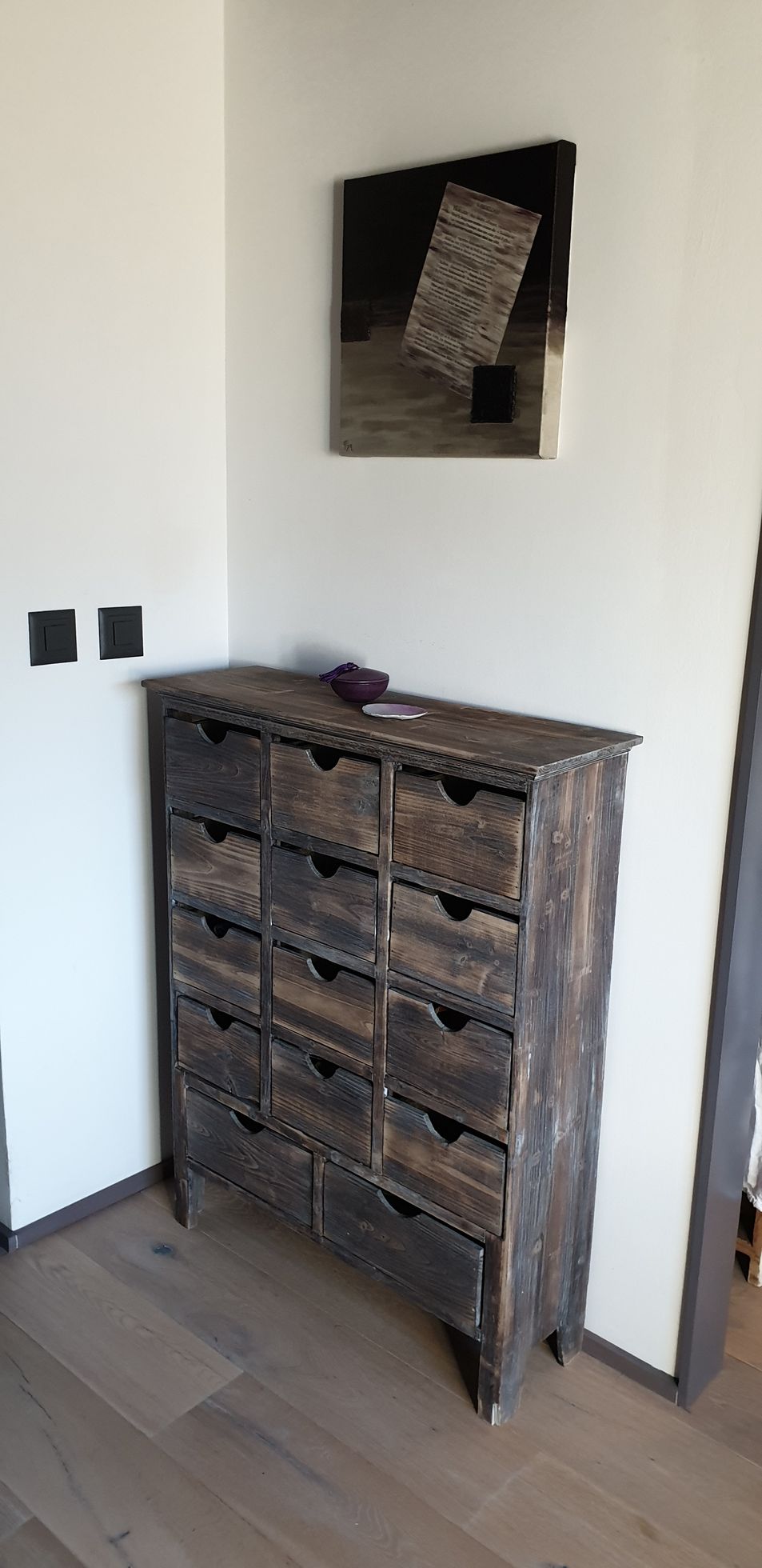 Une commode en bois se trouve dans un coin d'une pièce.