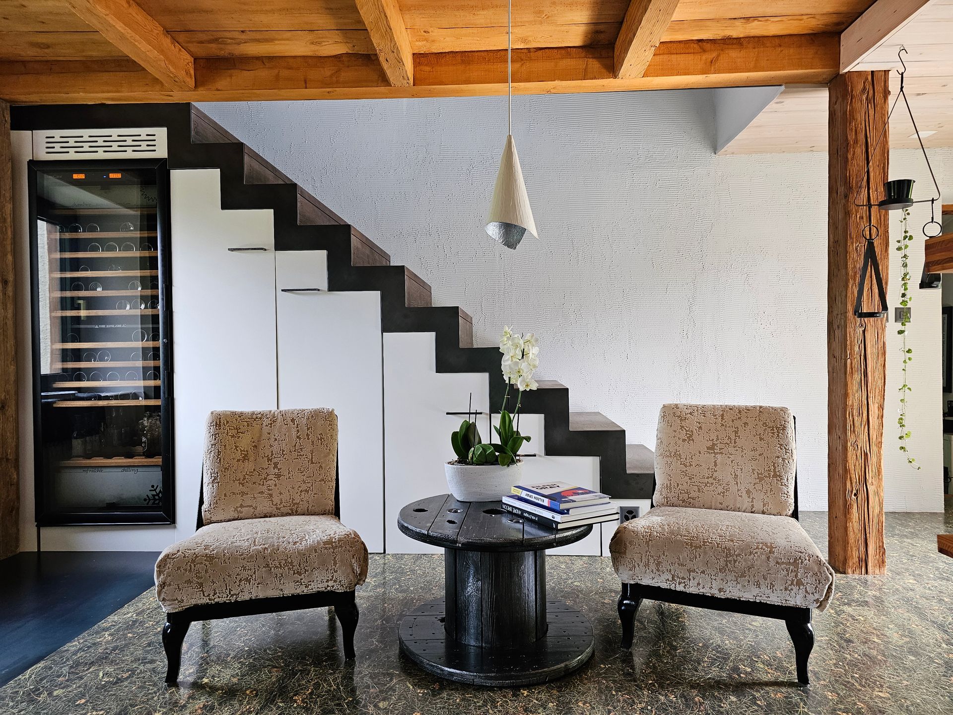 Un salon avec deux chaises et une table sous un escalier.