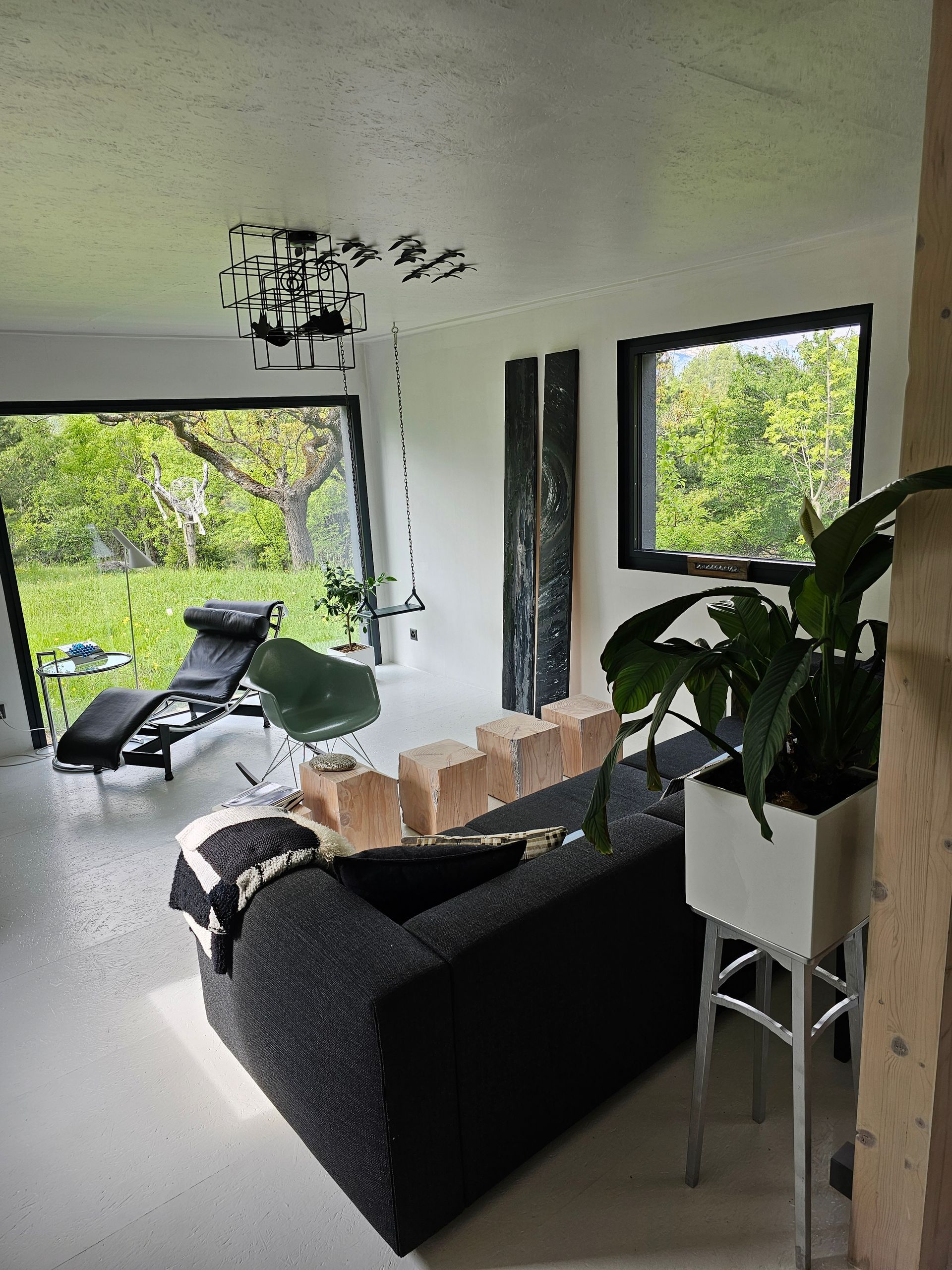 Un salon avec un canapé noir et une grande fenêtre