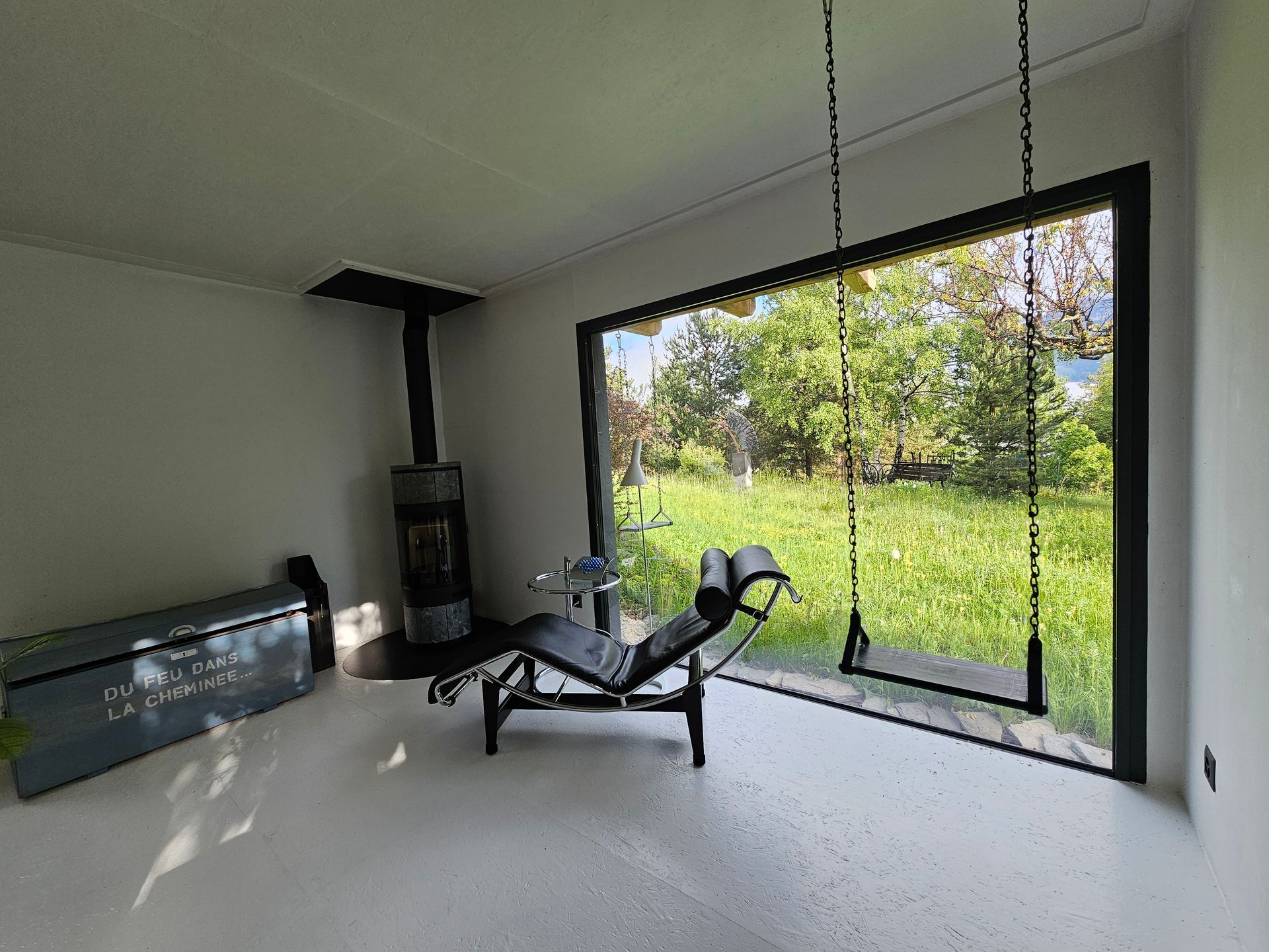 Un salon avec une grande fenêtre , une chaise et une cheminée.