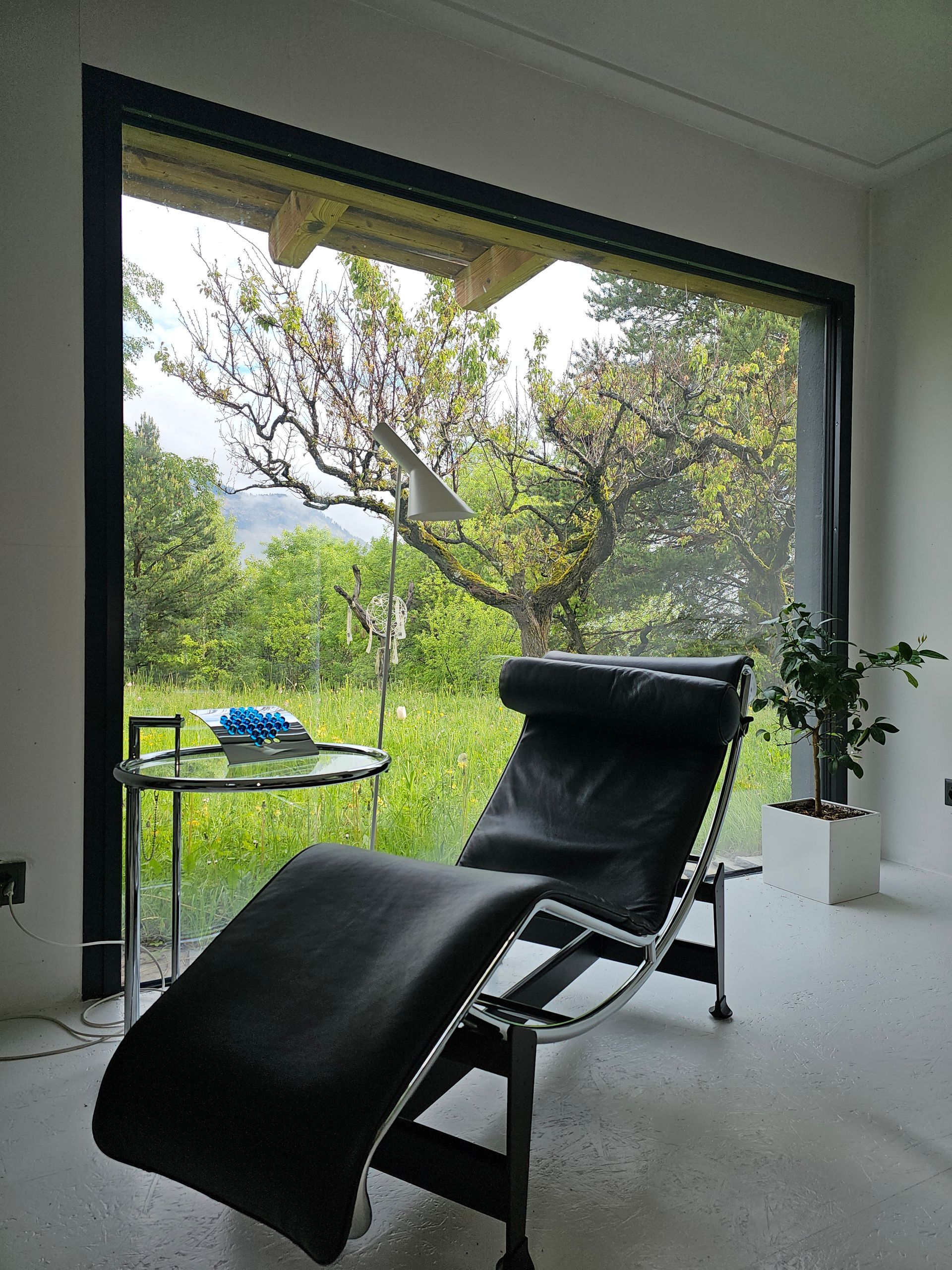 Une chaise noire est assise devant une grande fenêtre