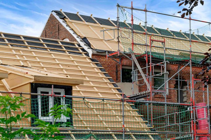 Das Dach eines Hauses wird gebaut und ist von einem Gerüst umgeben.