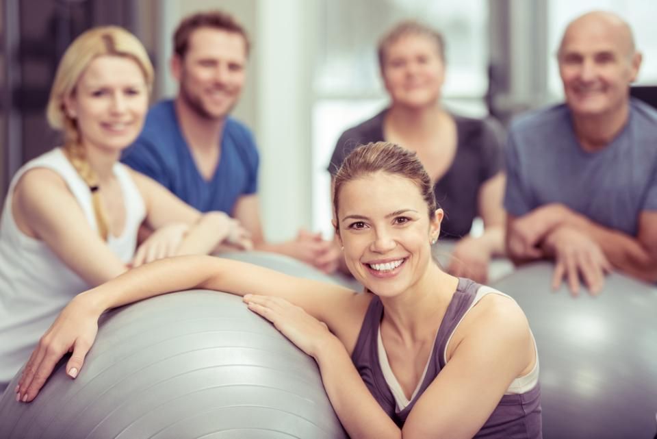 PV Gesundheitstraining - Drei Personen in einem dunklen Fitnessstudio machen Kniebeugen