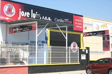 Un coche rojo está estacionado frente a una tienda llamada José Luis.